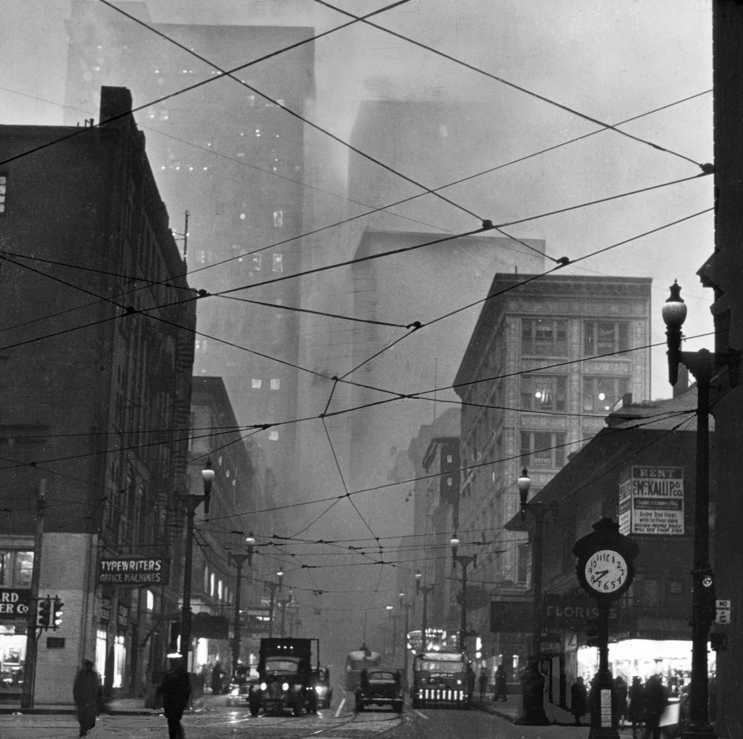 Vista a pie de calle de la esquina de Liberty y Fifth Avenues en Pittsburgh con un reloj en el marco, tomada a las 8:38 a. m., alrededor de 1940. Durante más de un siglo, Pittsburgh estuvo marcada como una ciudad llena de humo. En 1941 se aprobó una ordenanza efectiva de control de humo en la ciudad de Pittsburgh, pero el inicio de la Segunda Guerra Mundial retrasó la promulgación de la legislación hasta 1946.