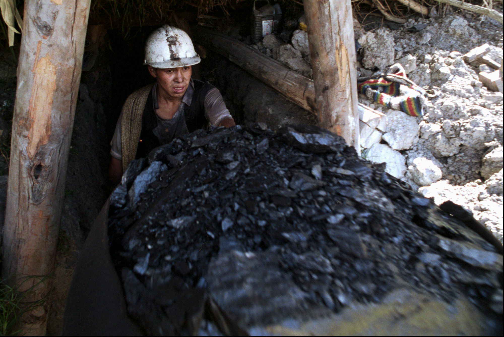 Un trabajador del carbón empuja un carro lleno de combustible fuera de una mina en la ciudad de Topaga, en el centro de Colombia, en esta foto de febrero de 1995.