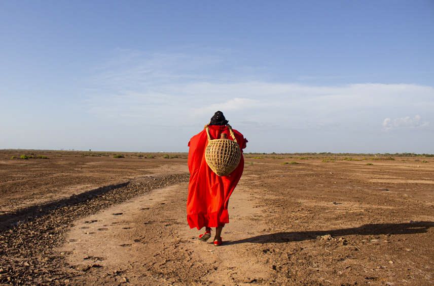 Una mujer carga una canasta mientras camina en tierra firme cerca del río Ranchería, donde vive la indígena wayú..