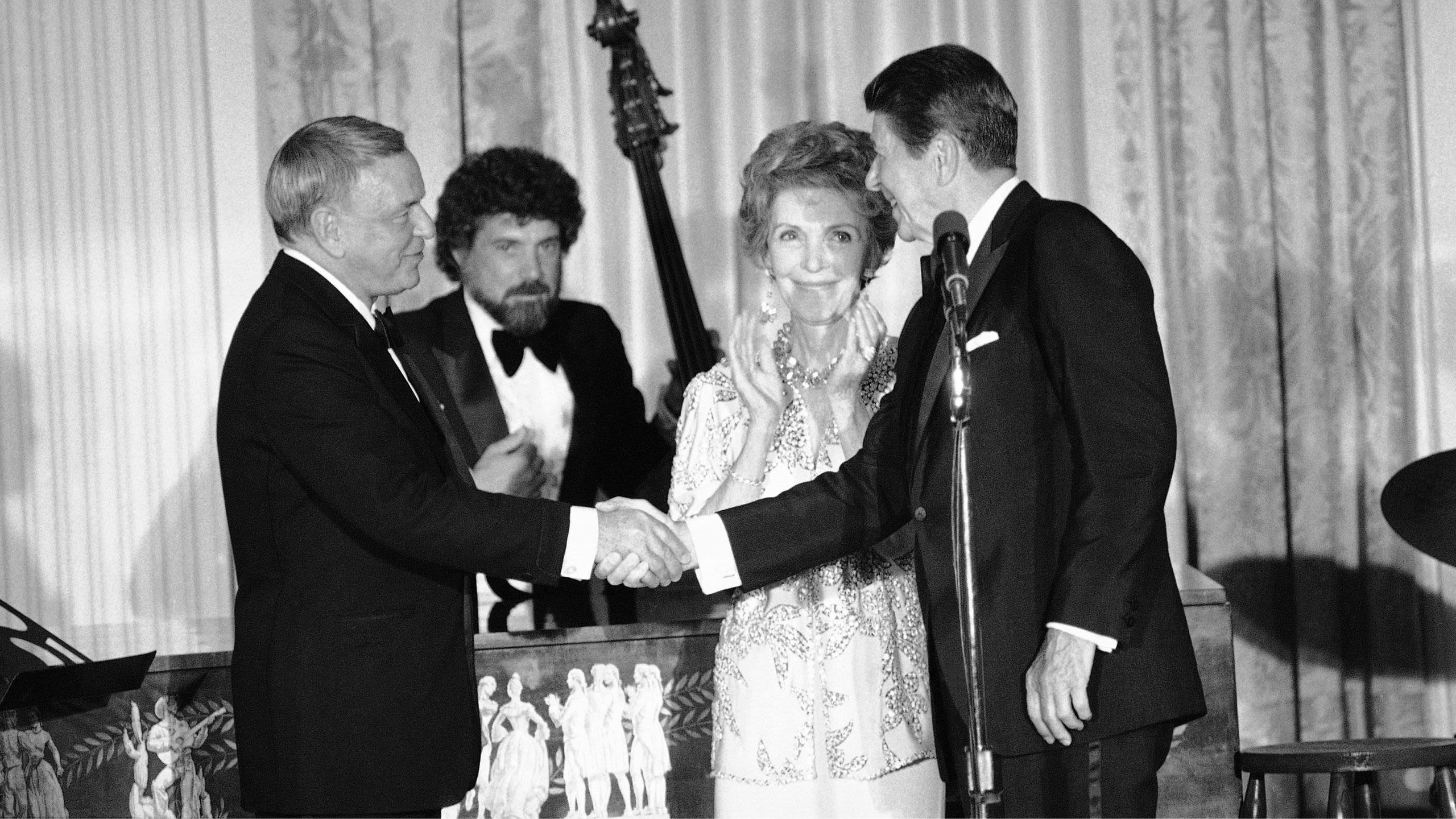 Frank Sinatra shaking hands with Ronald Reagan, Nancy Reagan clapping hands (© Scott Stewart/AP)
