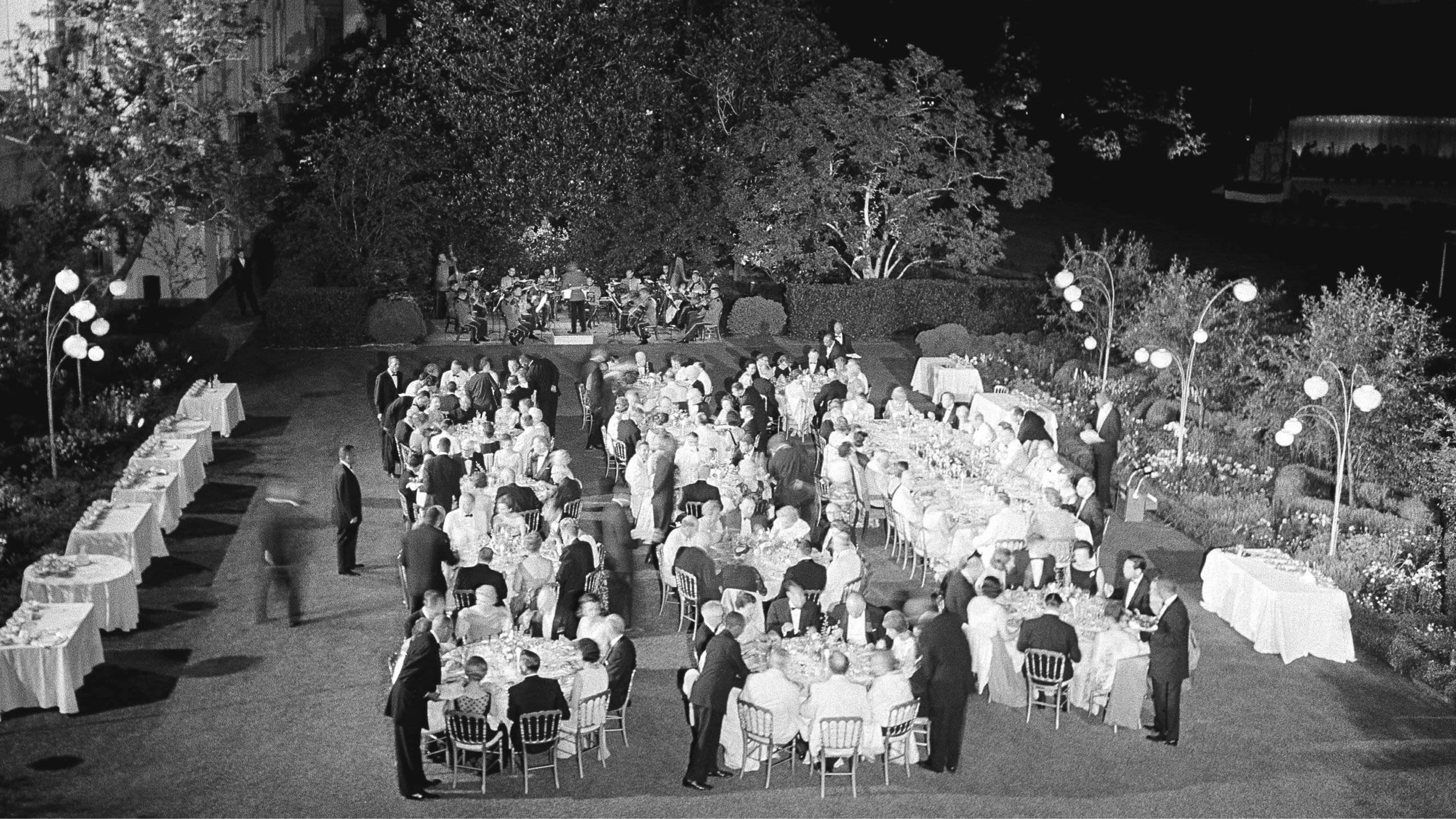 Waiters serving food during outdoor dinner (© WCA/AP)