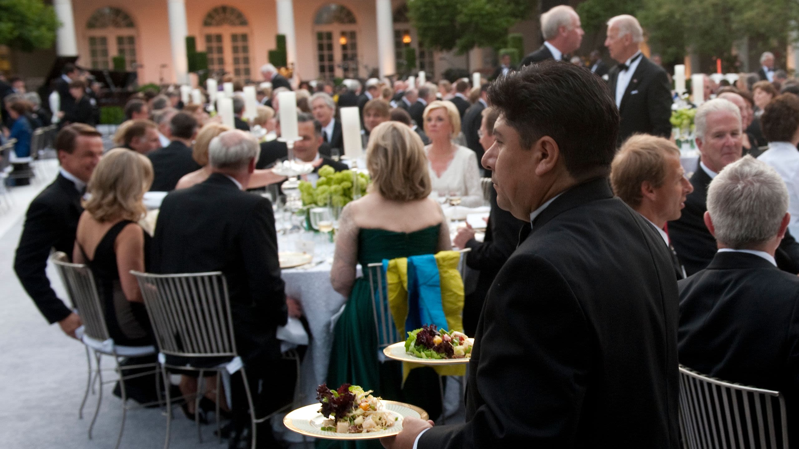 Waiter delivering food at outdoor dinner (© Saul Loeb/AFP/Getty Images)