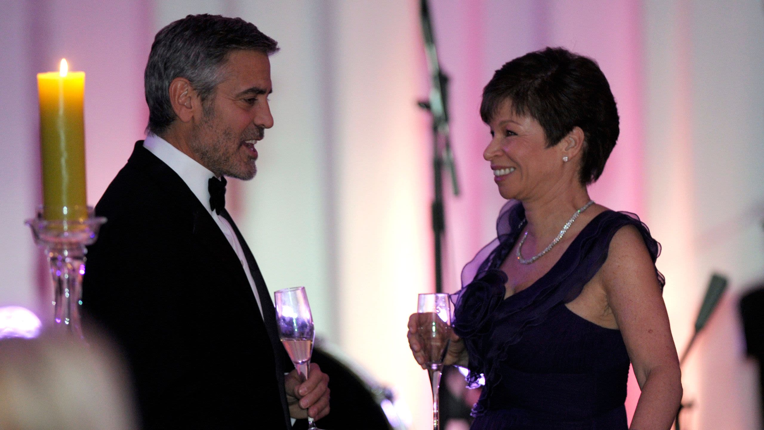 George Clooney chatting with Valerie Jarrett, both holding drinks (© Susan Walsh/AP)