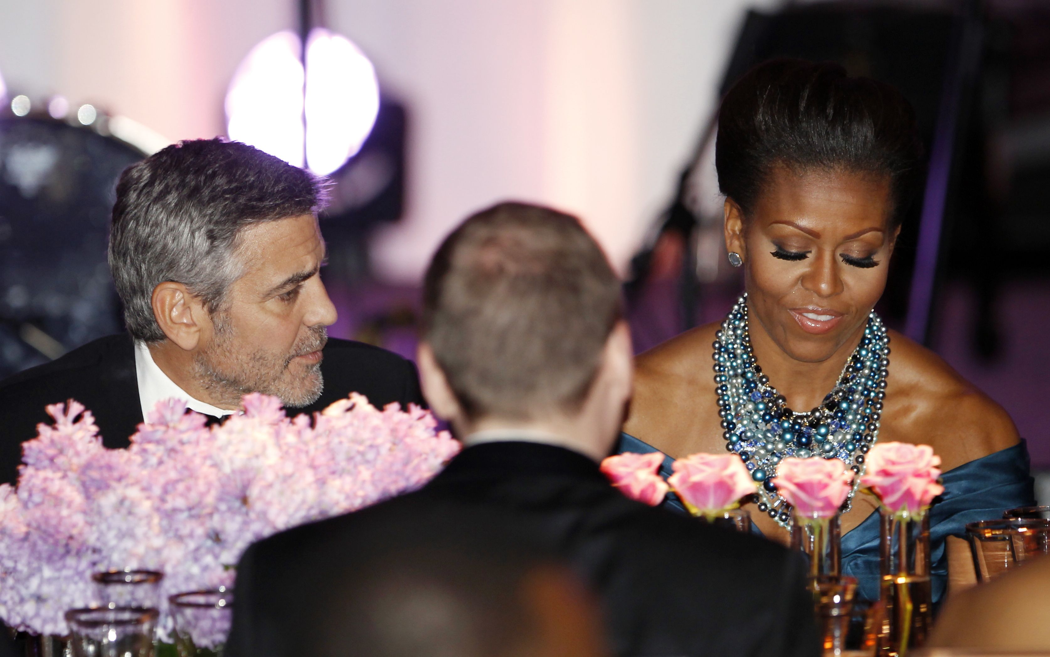 George Clooney looking at Michelle Obama at table decorated with flowers (© Kevin Lamarque/Reuters)