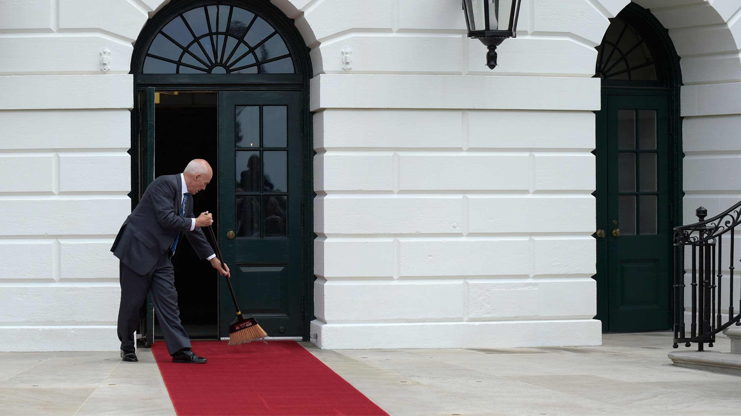 Daniel Shanks sweeping red carpet in a White House doorway. (© Susan Walsh/AP)