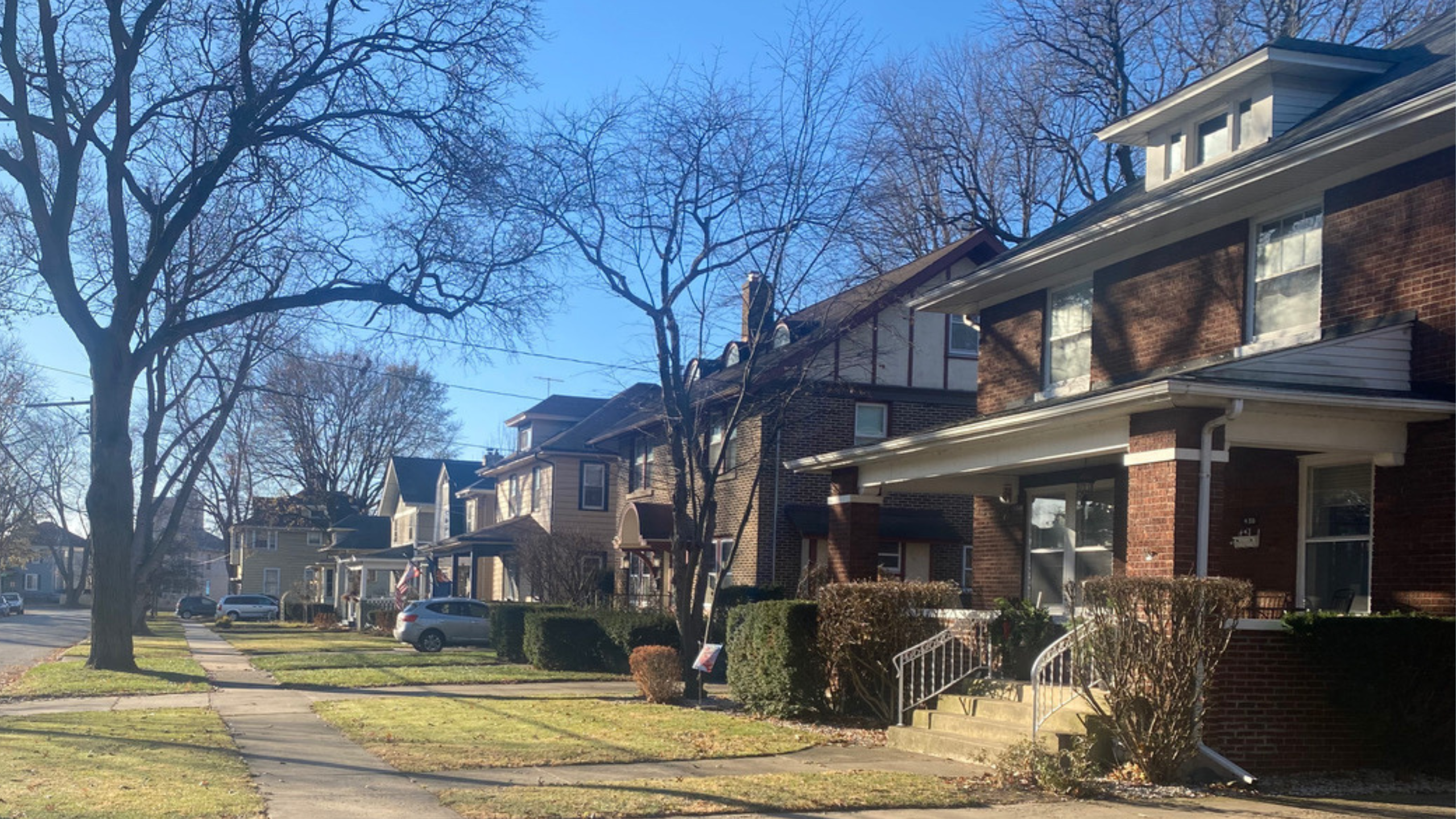 four two-story houses on a tree-lined street