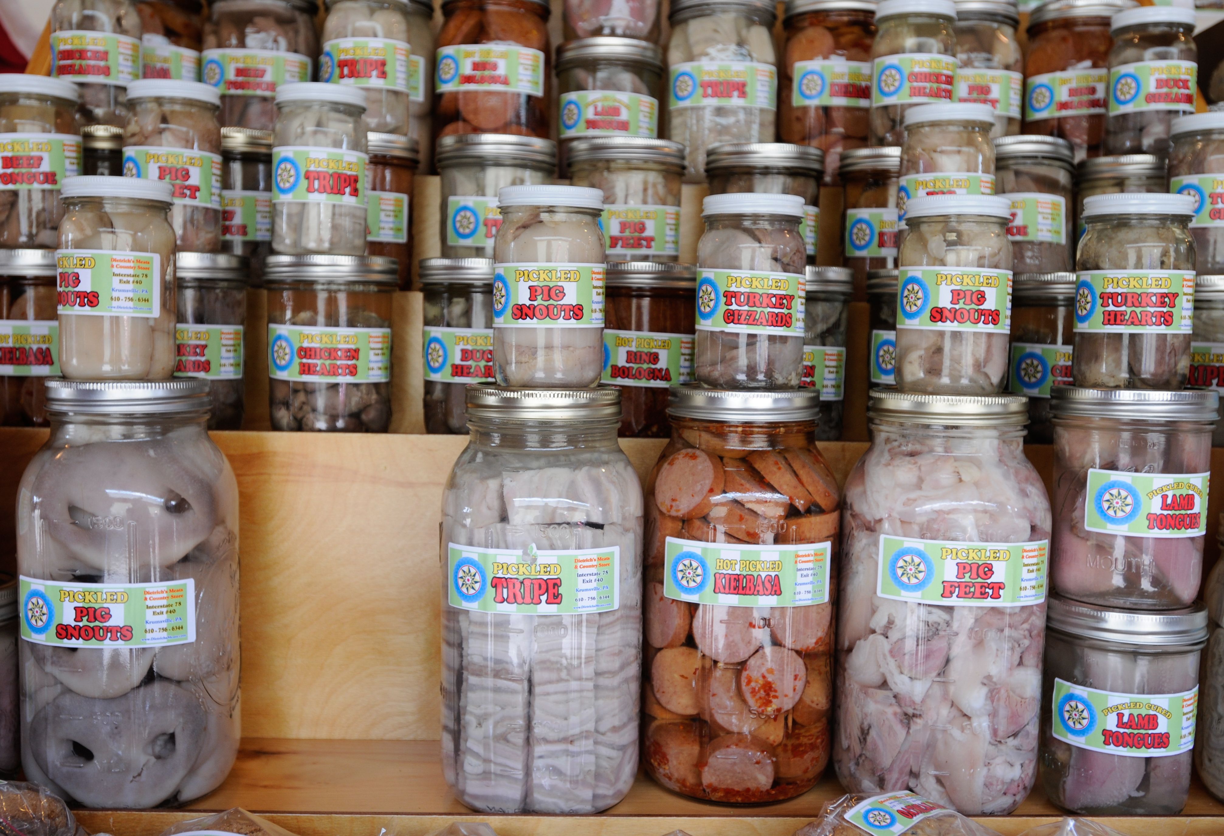 a display of mason jars filled with pig snouts, tripe, and pig's feet