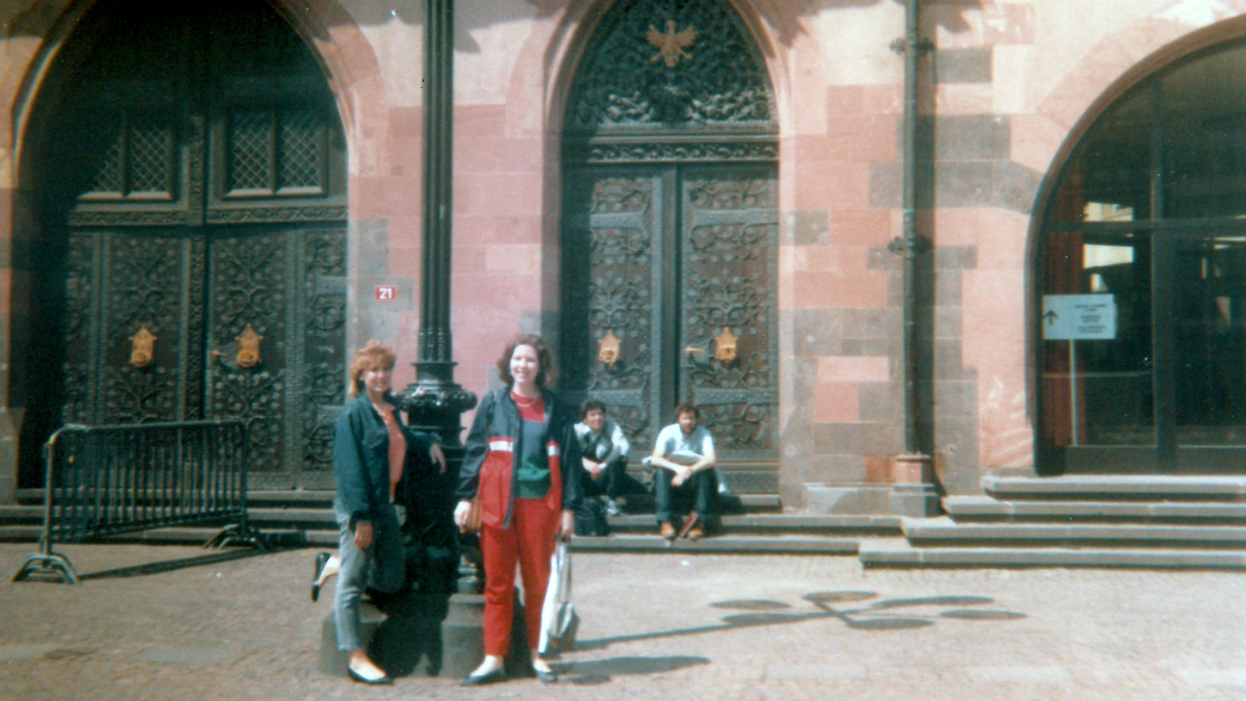 two women stand in front of a historic building with very large arched doorways