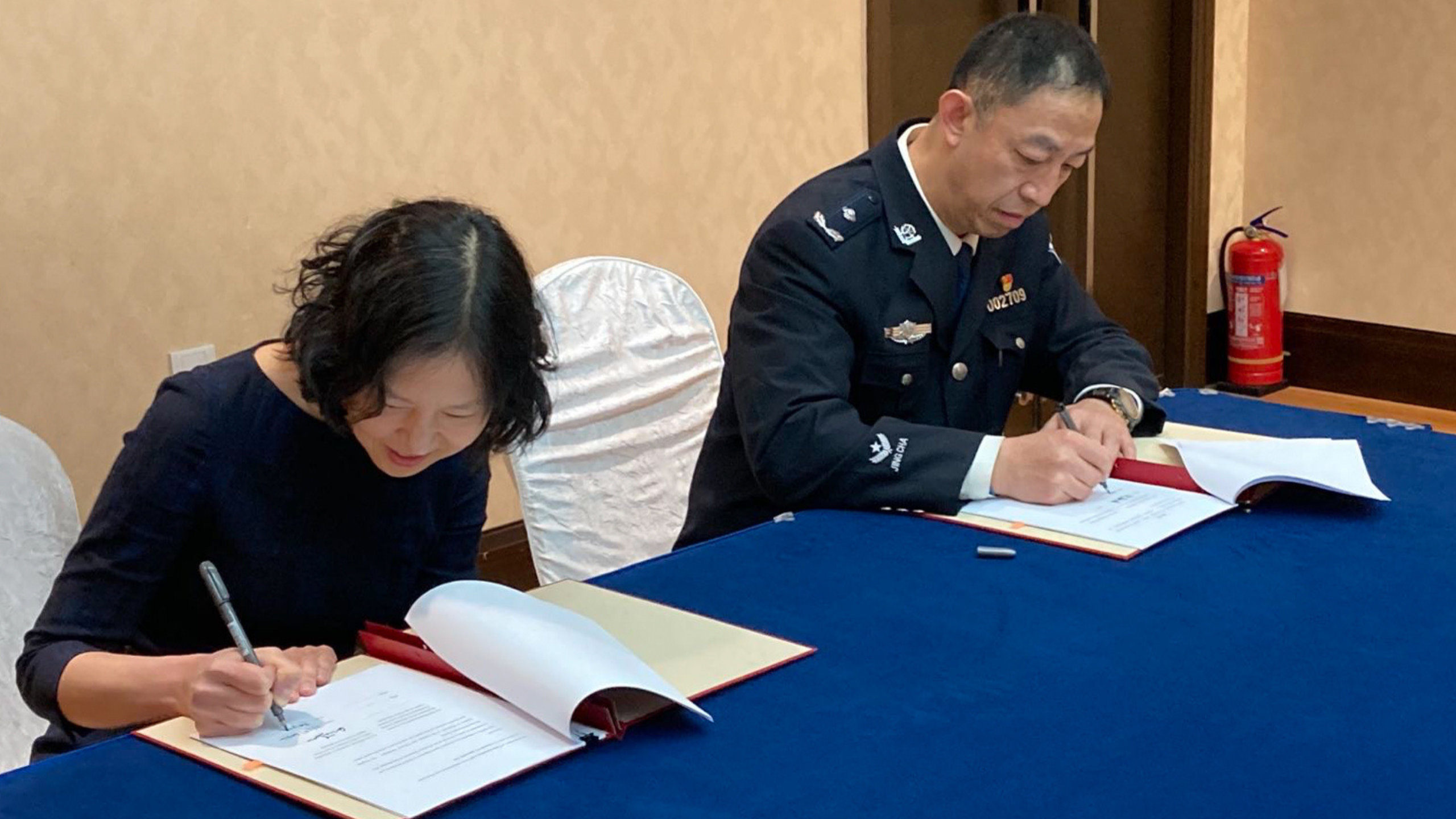 a woman and a man wearing a uniform sit at a table signing documents