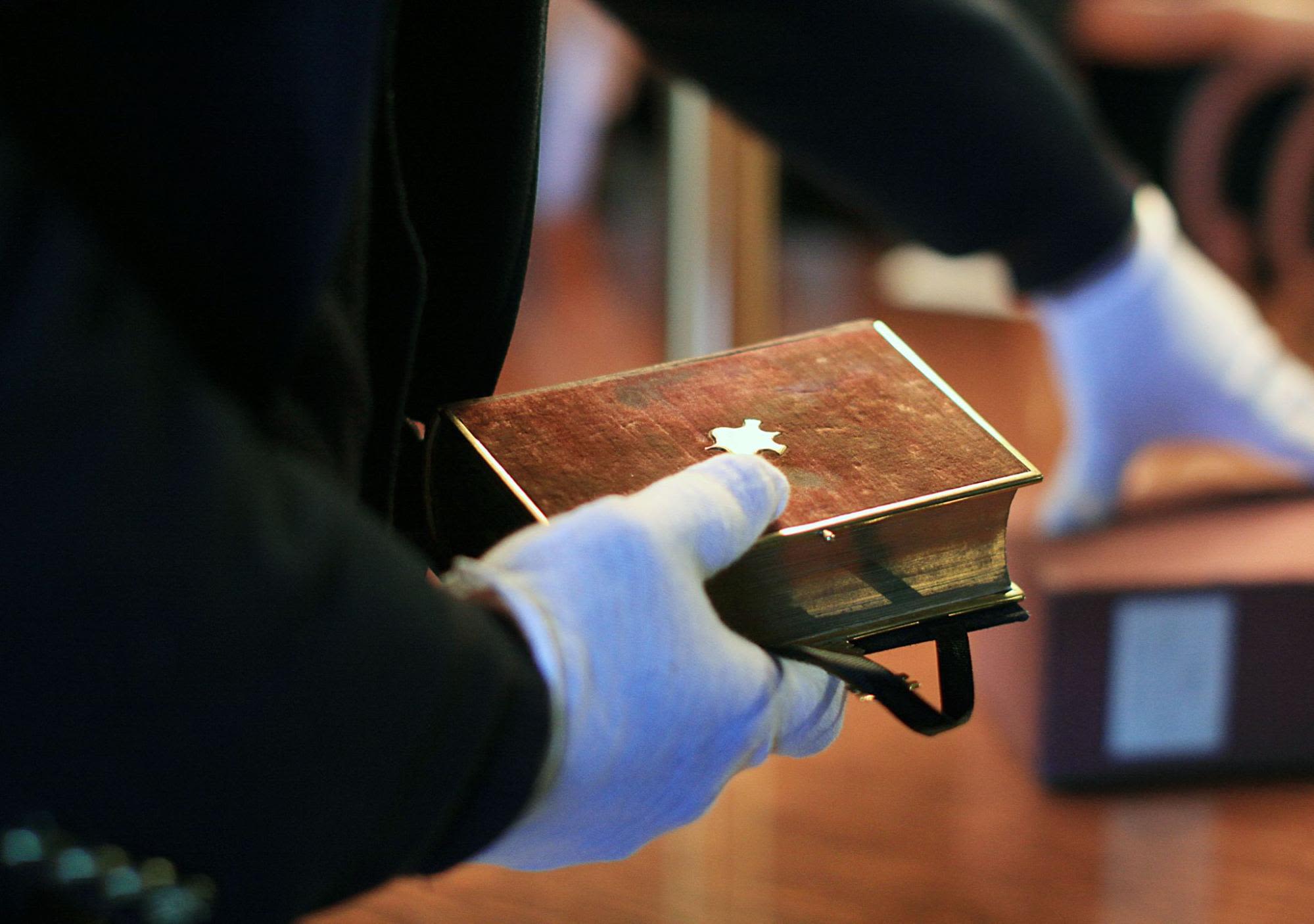 Close-up of a gloved hand holding a historic Bible (© Lauren Victoria Burke/AP)