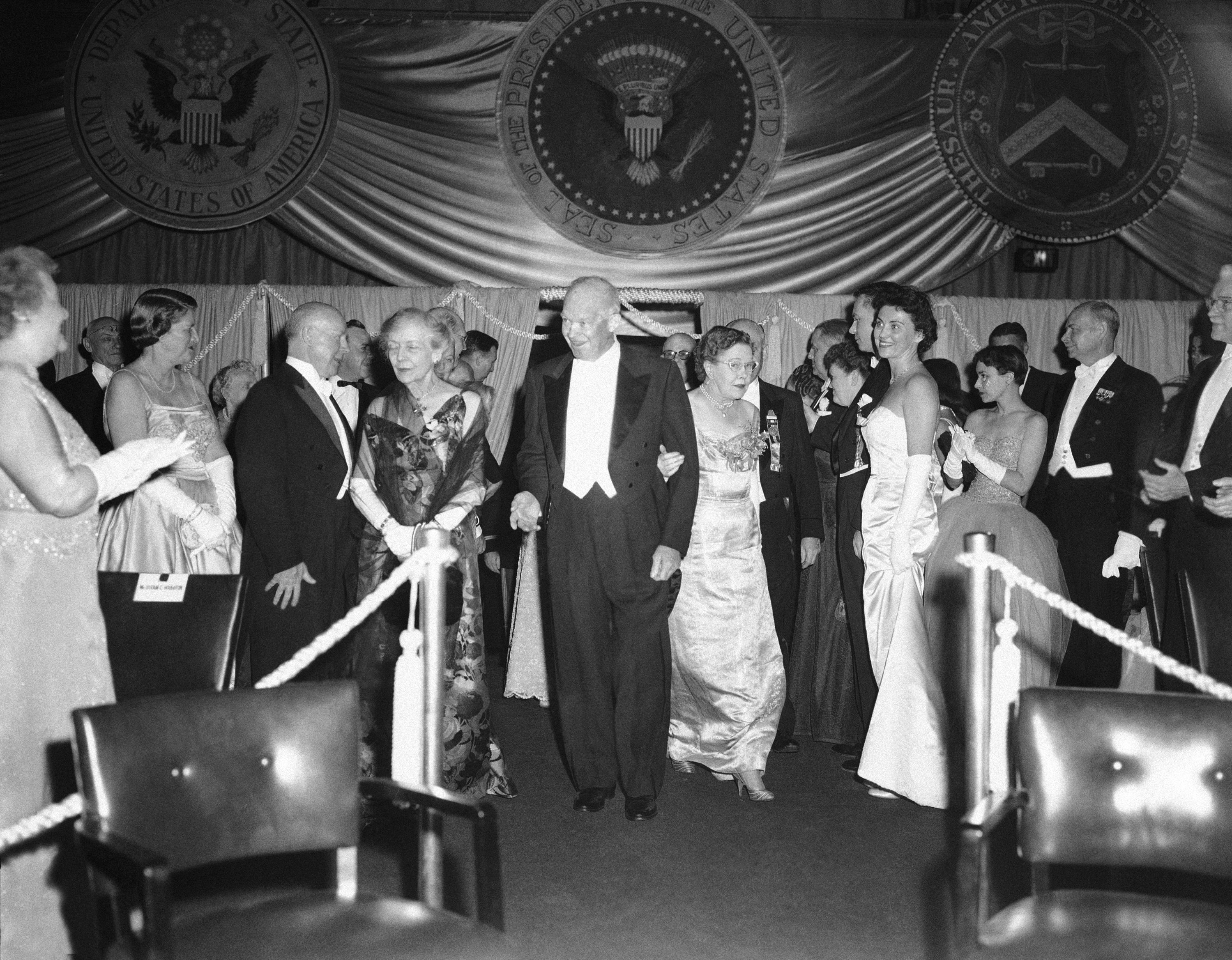 Dwight D. Eisenhower attending an inaugural ball, surrounded by elegantly dressed guests and decorations with the presidential seal (© AP)
