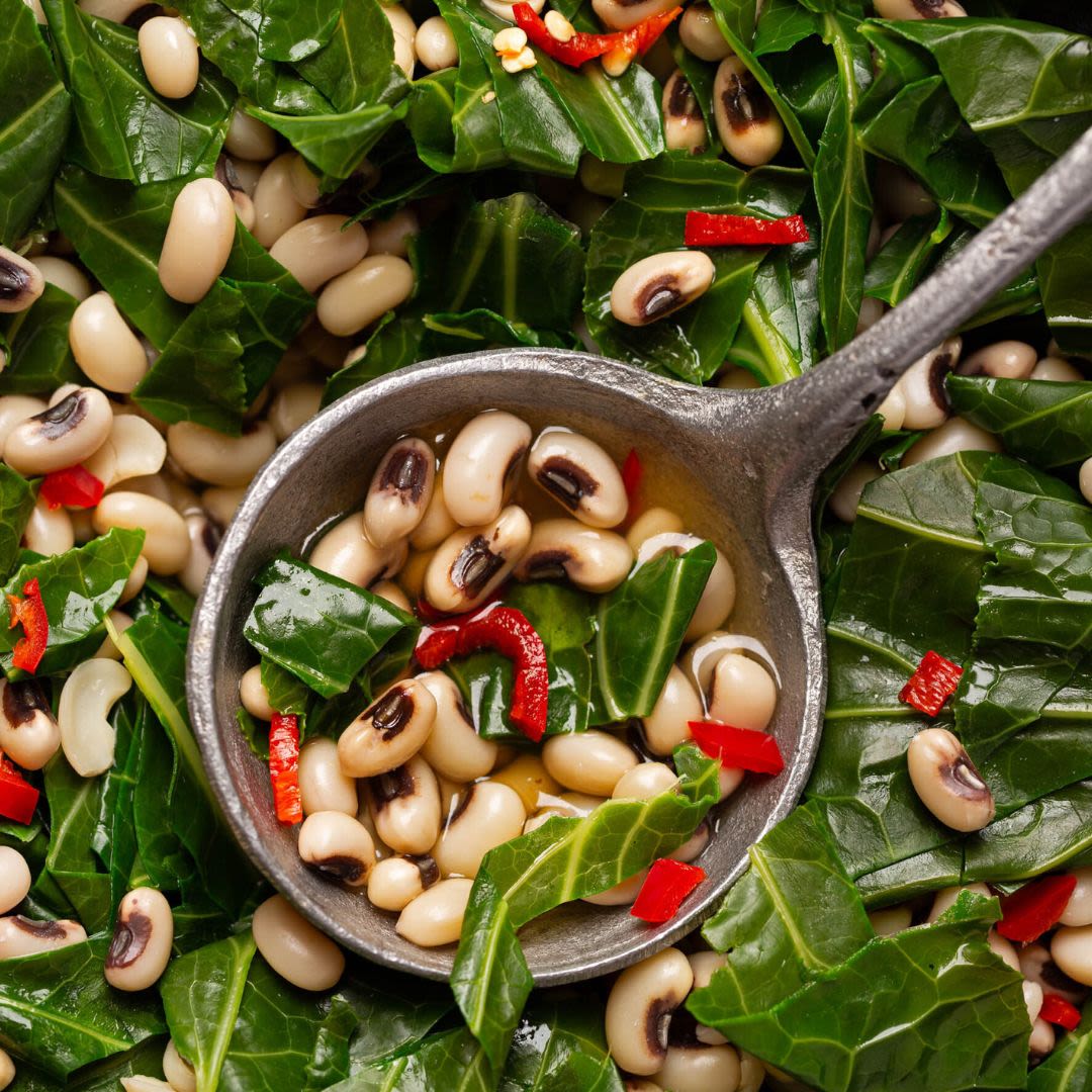 A close-up of black-eyed peas and collard greens with diced red peppers, symbolizing traditional New Year’s food