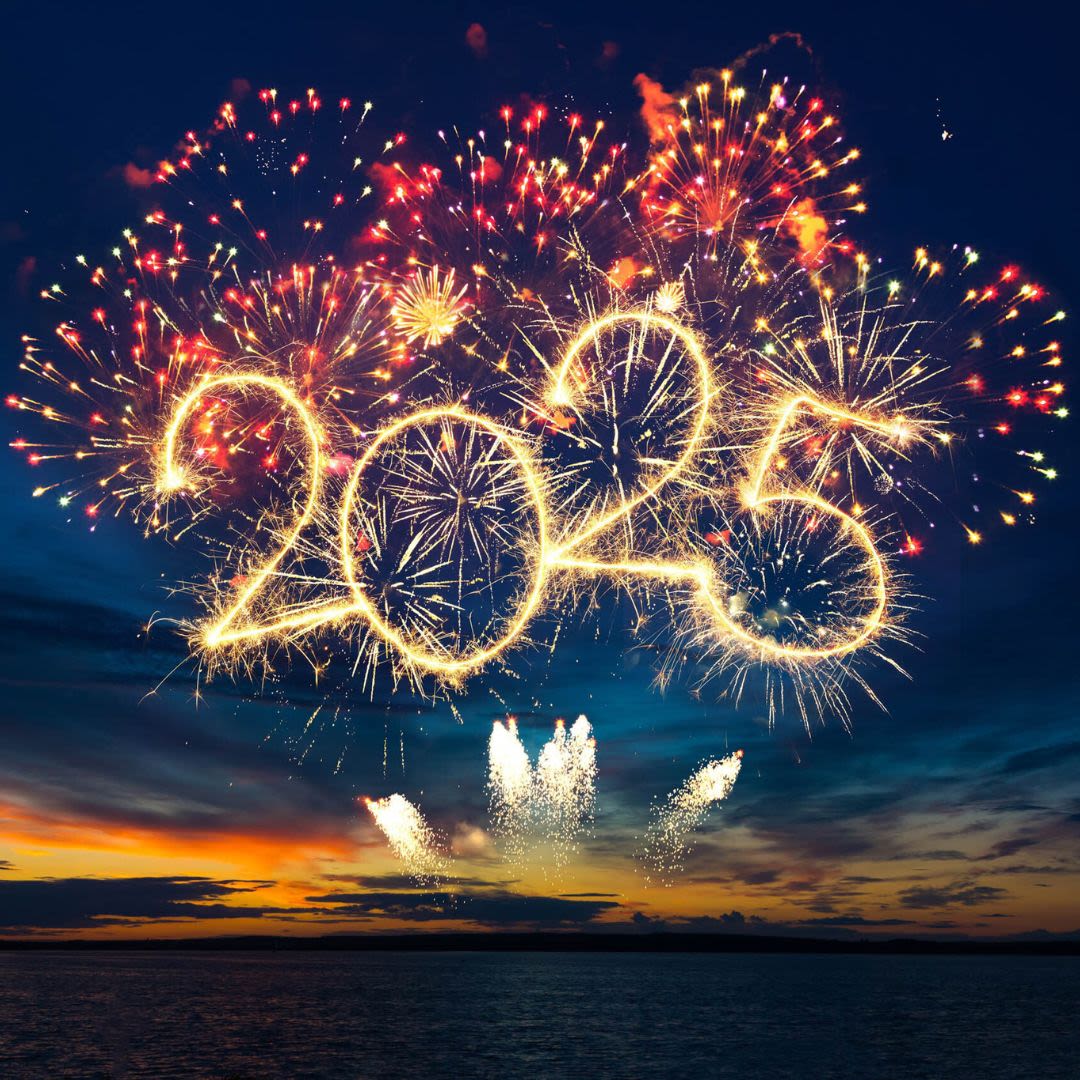 Fireworks lighting up the sky, forming the glowing numbers "2025" over a dark horizon at sunset