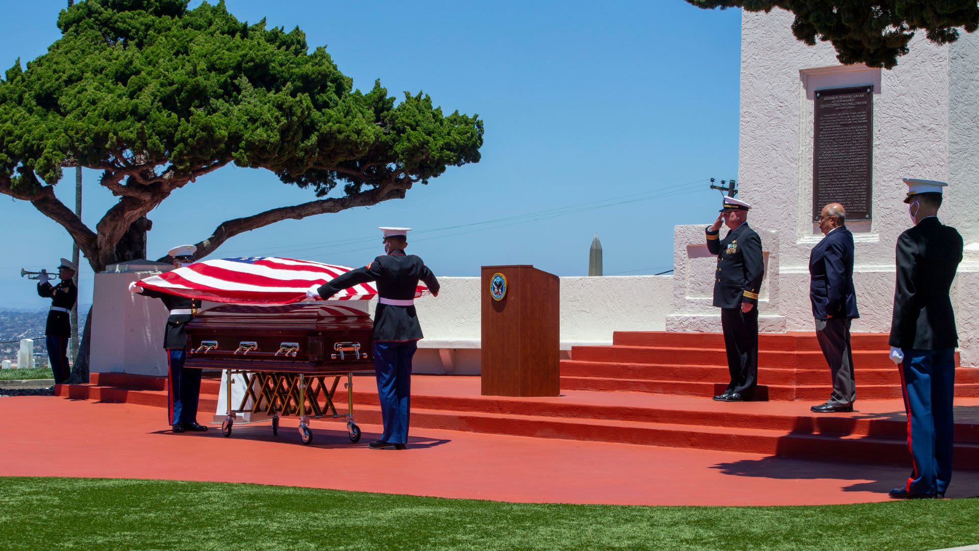 2 service members draping flag on casket while other people stand by at Fort Rosecrans National Cemetery (U.S. Marine Corps/Lance Corporal Kerstin Roberts)
