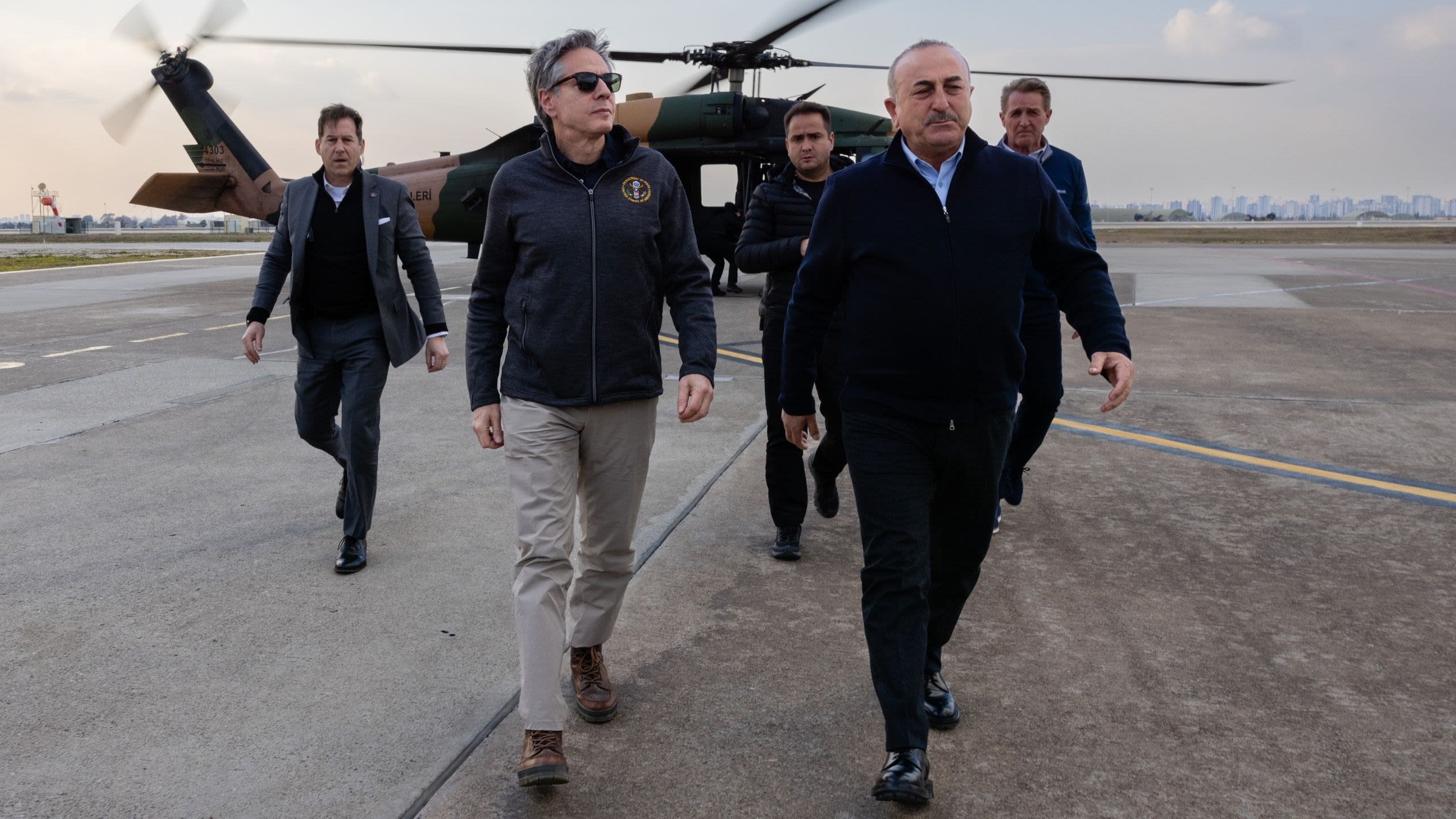 5 men walking on a tarmac away from a helicopter