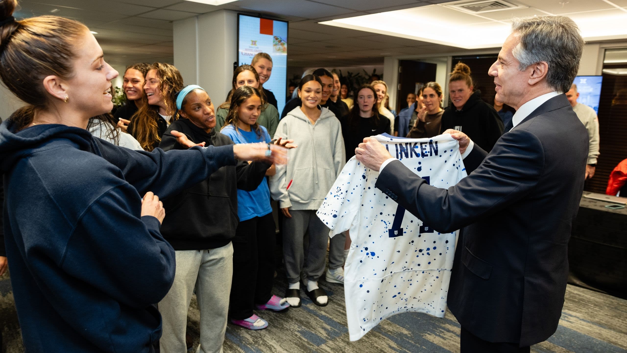 Secretary Blinken holding up a soccer jersey in front of soccer team