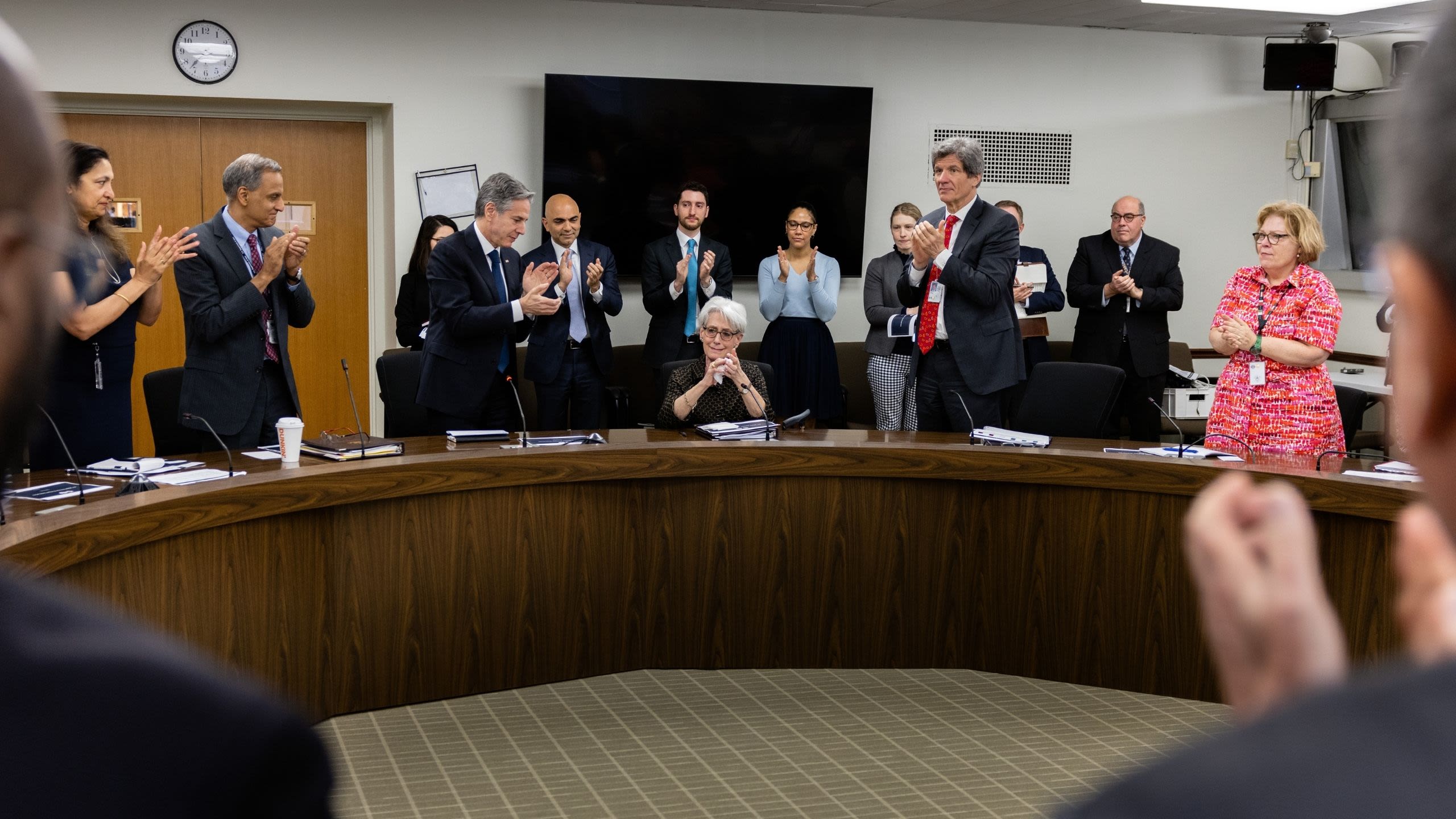 People giving standing ovation to a seated woman