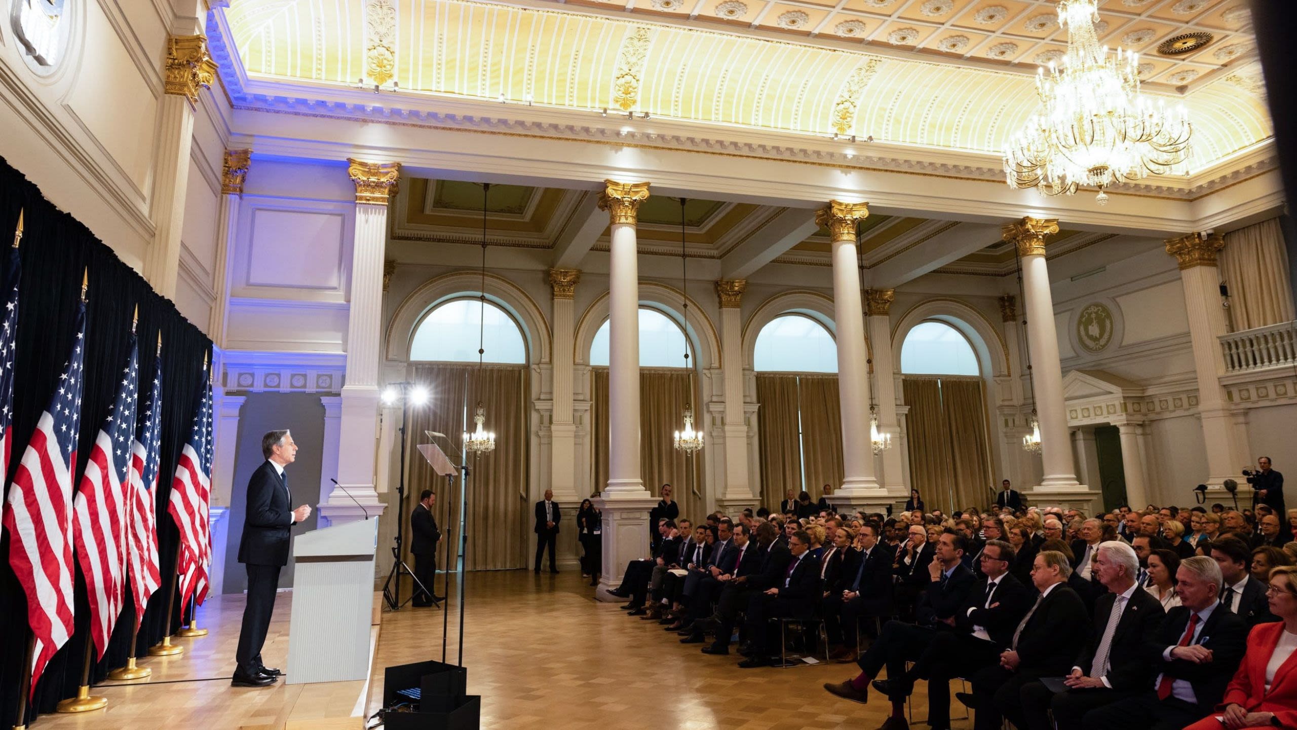 Secretary Blinken standing at a lectern while speaking to a room full of people
