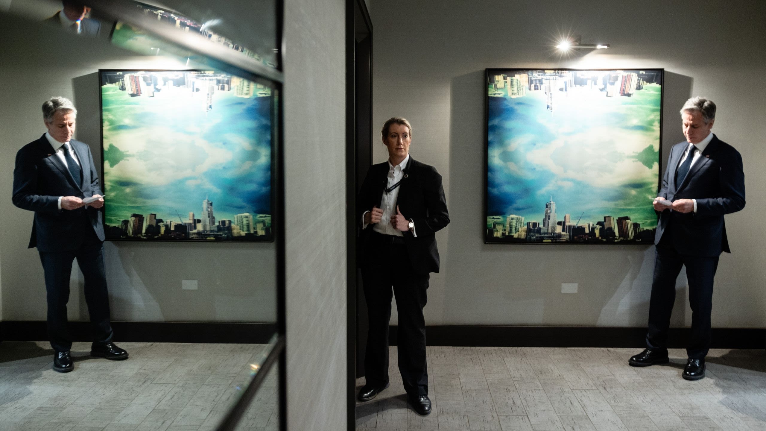 Secretary Blinken looking at his notes while Diplomatic Security agent stands in doorway