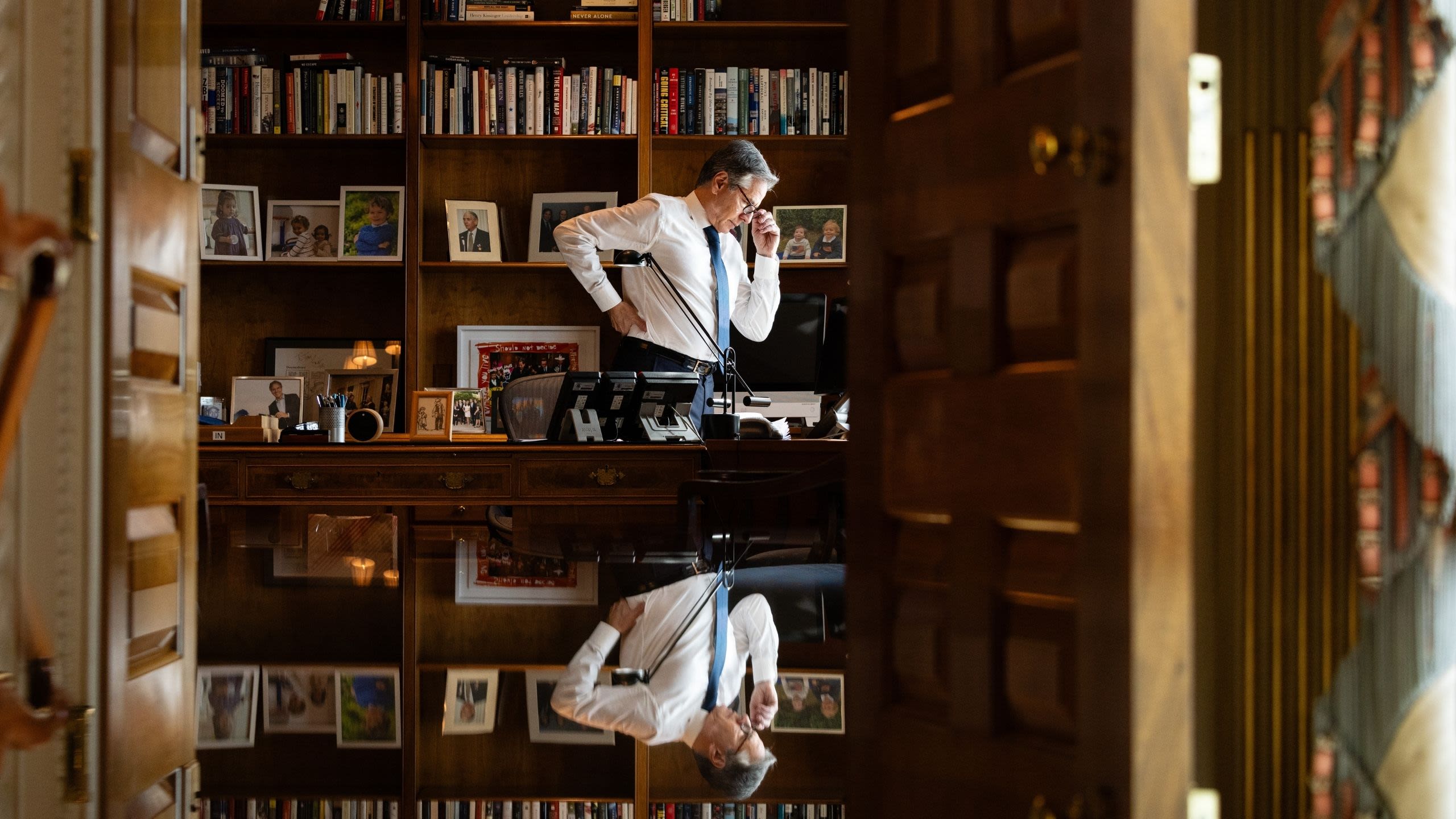 Secretary Blinken standing over his desk