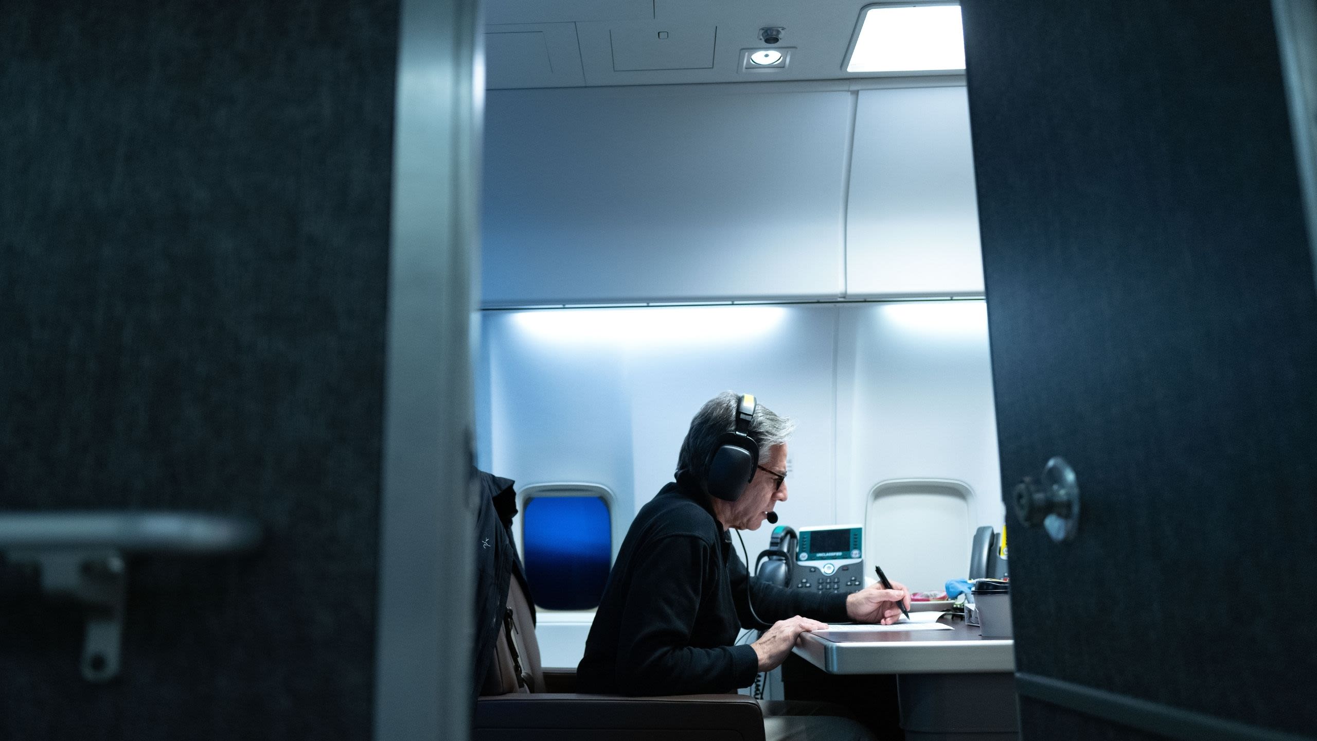 Secretary Blinken writing at a desk on a plane