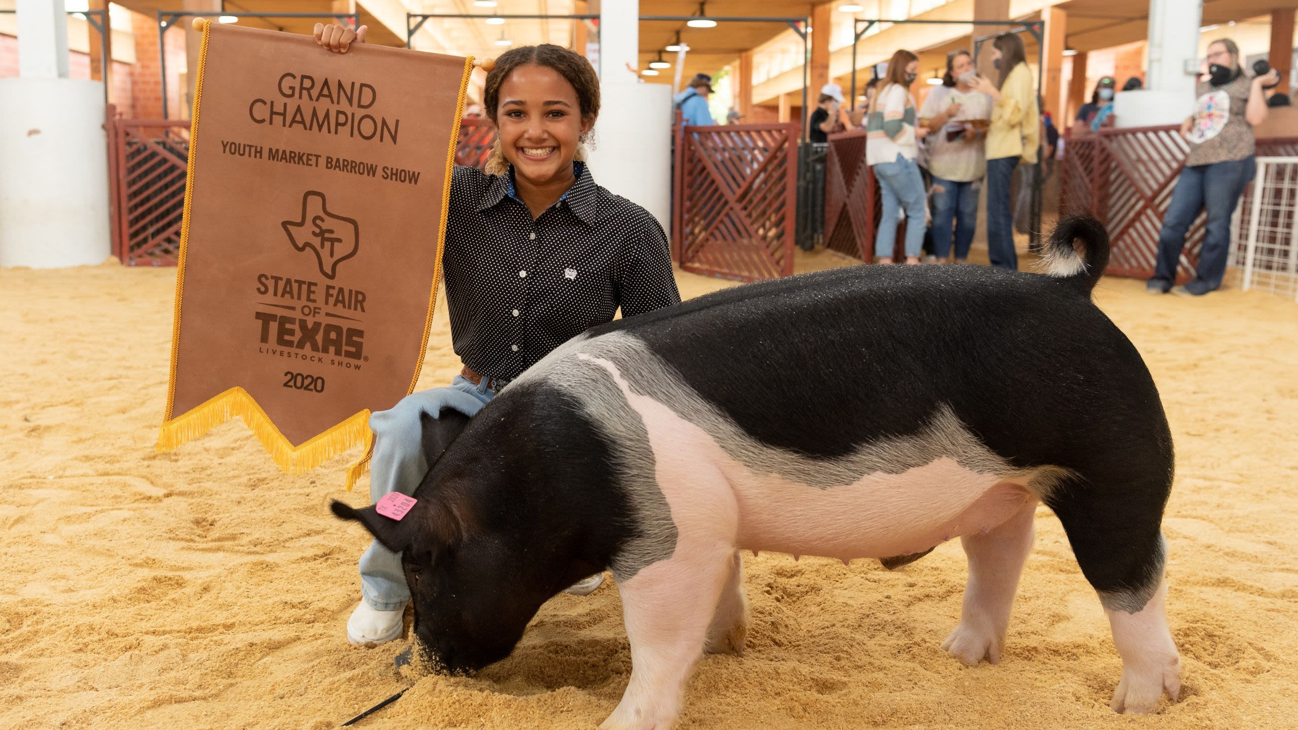 Girl holding a Grand Champion banner next to her prize-winning pig (Courtesy of State Fair of Texas)