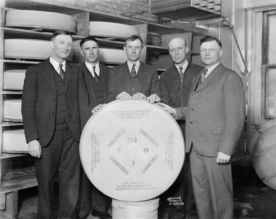 Five men posing with a large wheel of Wisconsin cheese (© Angus B. McVicar/Wisconsin Historical Society/Getty Images)