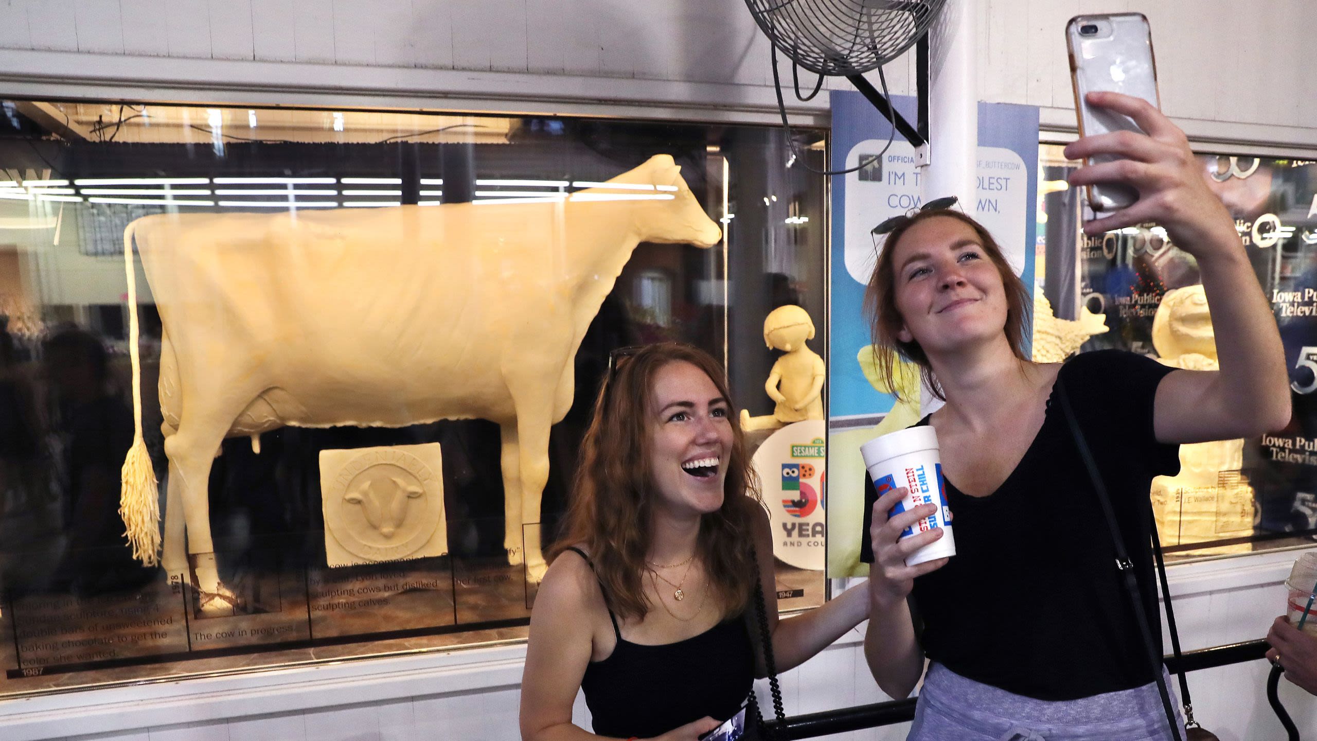 Two women taking a selfie in front of a life-sized butter cow sculpture (© Chip Somodevilla/Getty Images)
