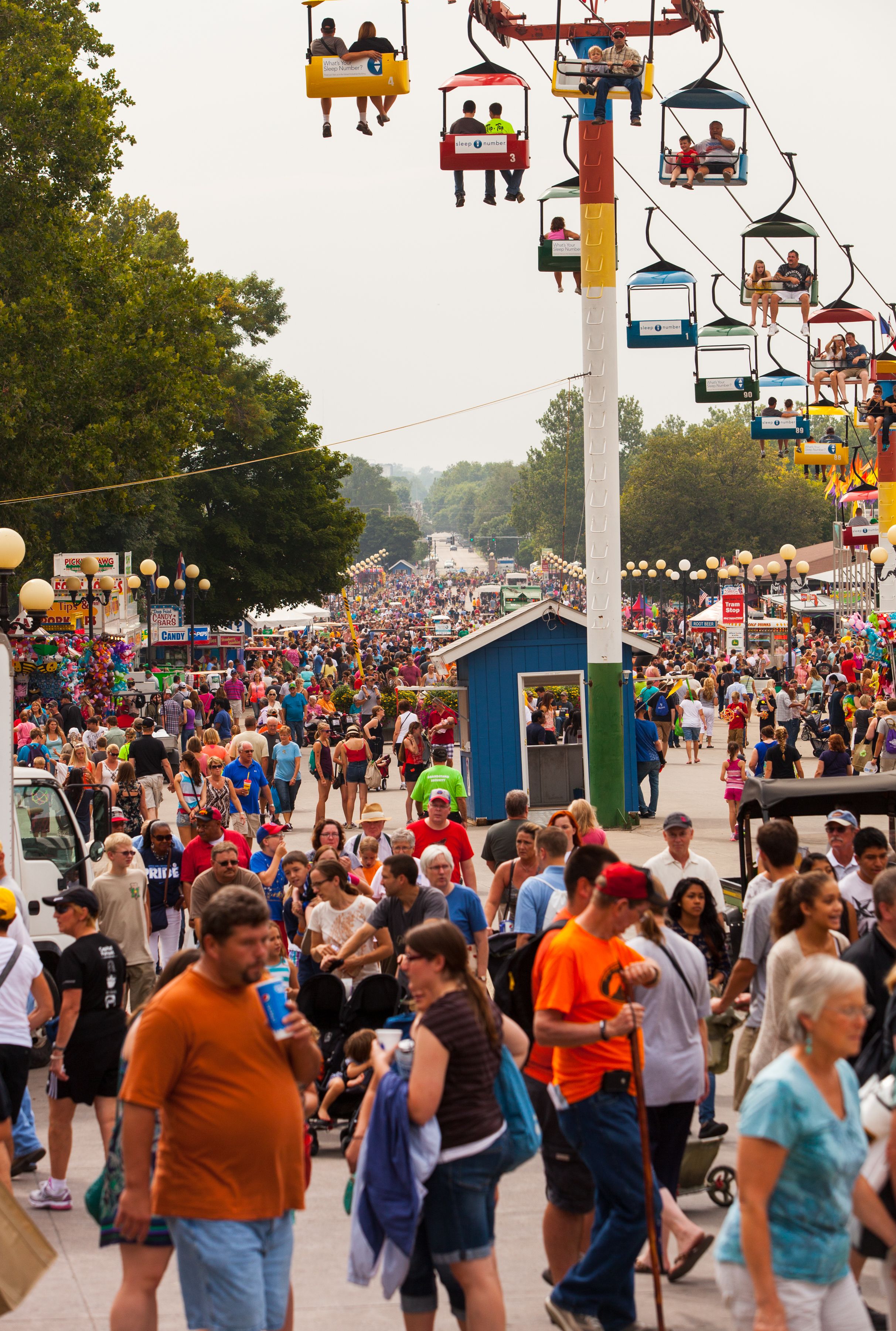 Large crowd walking beneath a chairlift at a busy state fair (© Shutterstock)