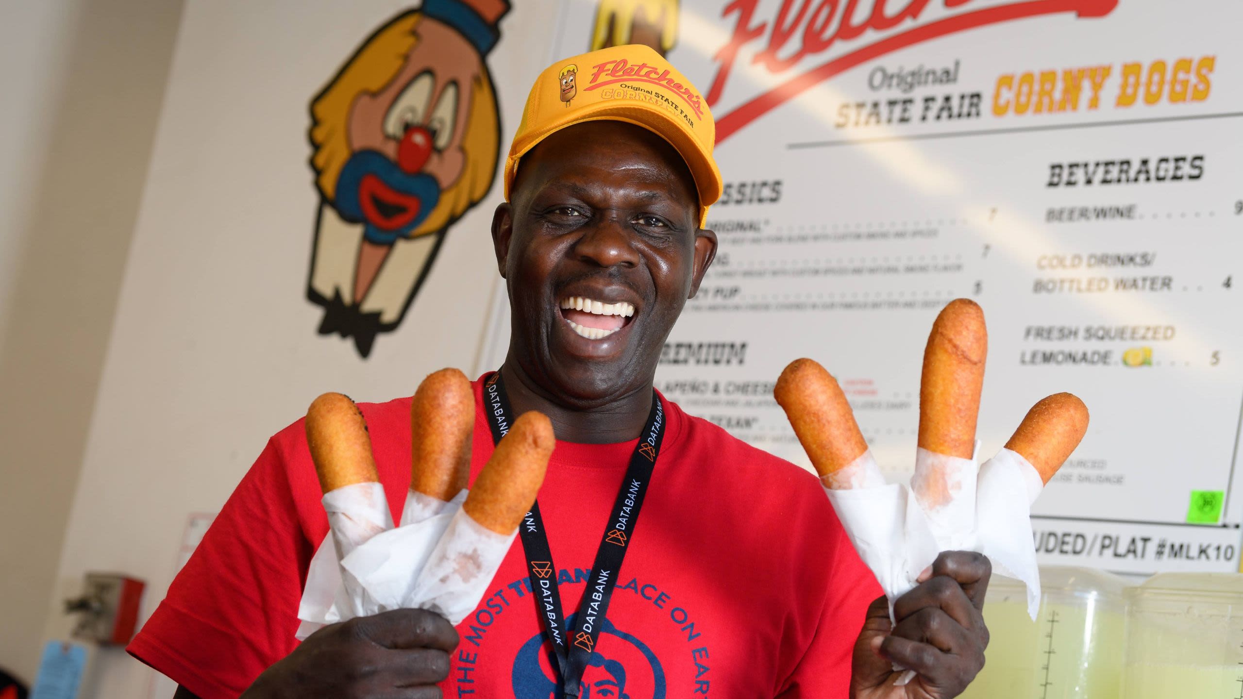 Smiling man holds six corn dogs at a concession stand (Courtesy of State Fair of Texas)