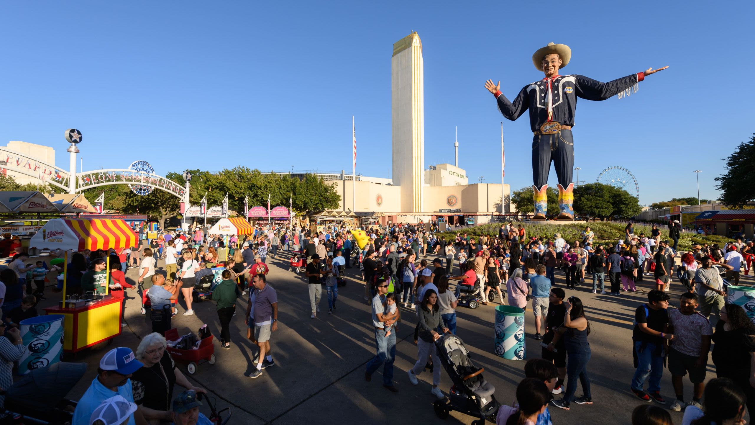 Crowds gather at the State Fair of Texas beneath the towering Big Tex statue on a sunny day (Courtesy of State Fair of Texas)