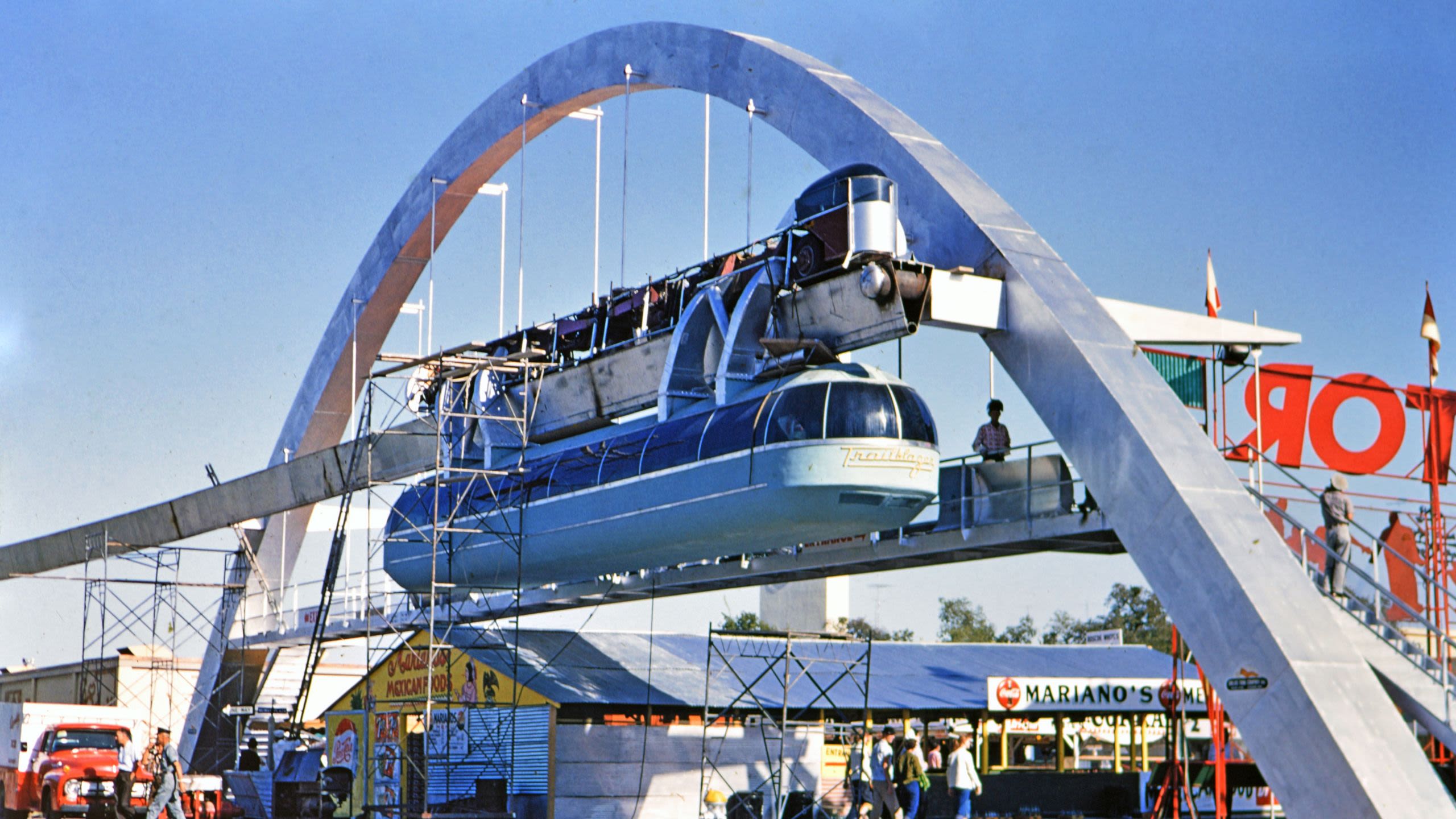 People walk beneath a futuristic monorail at the Texas State Fair, framed by a large metal arch (© HUM Images/Universal Images Group/Getty Images)