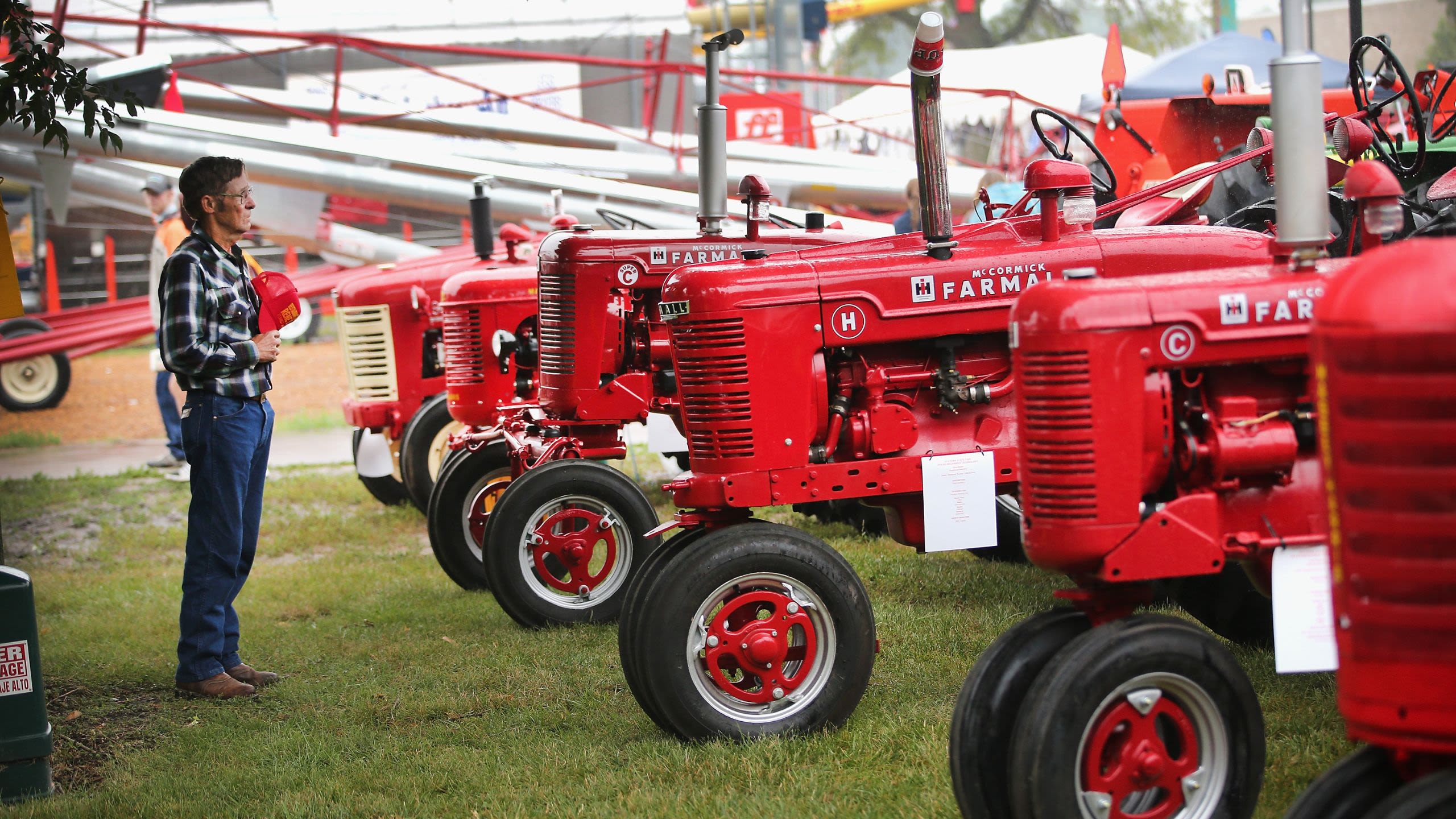 Man admiring a row of restored red tractors at an exhibit (© Scott Olson/Getty Images)