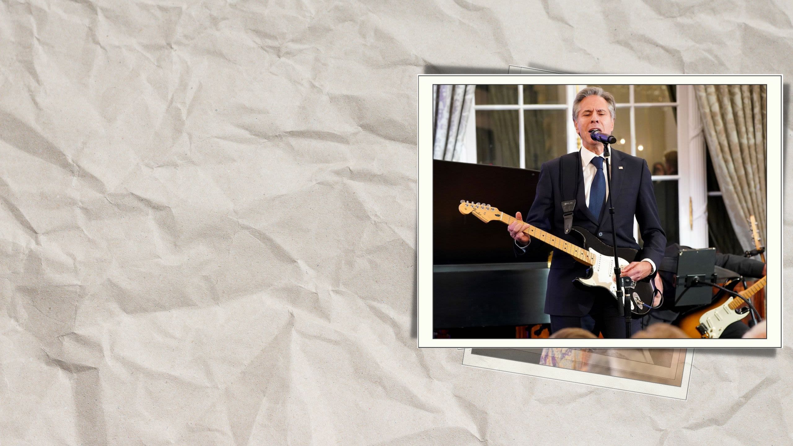 Secretary Blinken strumming a guitar and singing into a microphone (© Leigh Vogel/Getty Images)