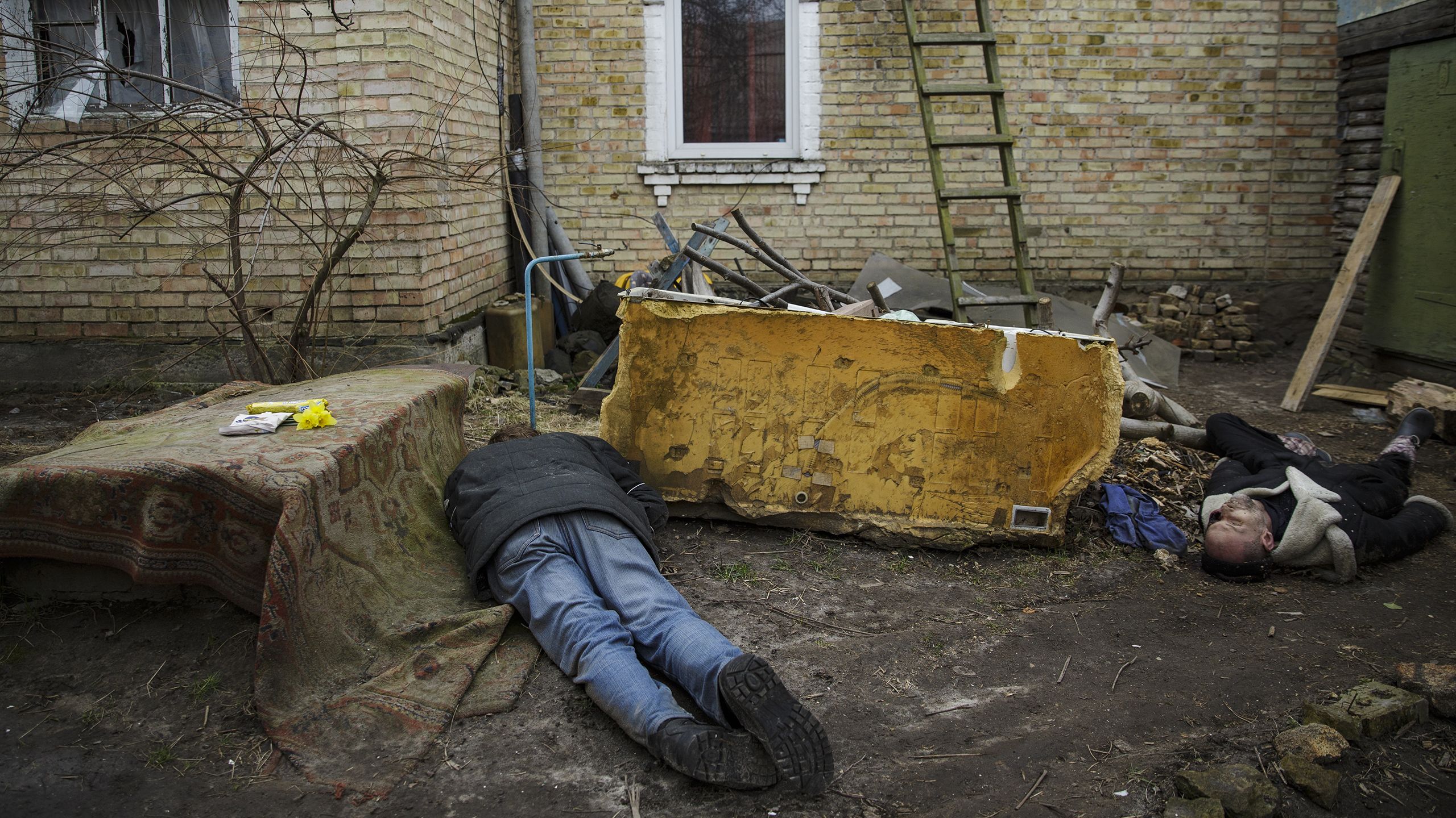 Deux hommes habillés en civil gisant dans une cour (© Oleg Pereverzev/Global Images Ukraine/Getty Images)