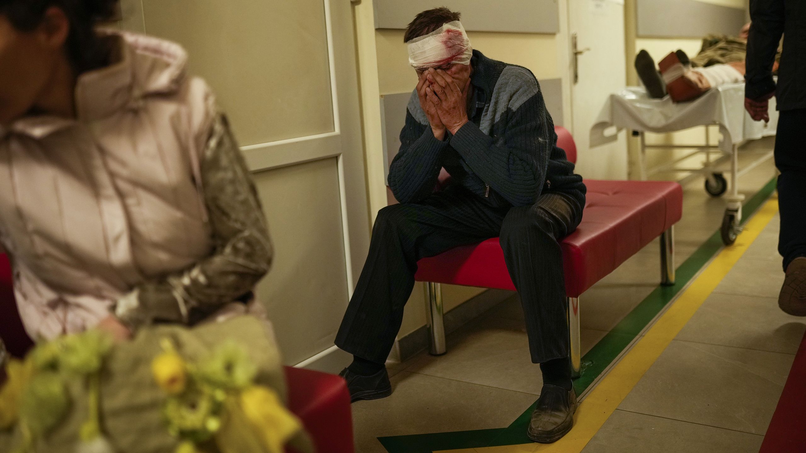 Un homme avec des bandages ensanglantés autour de la tête, assis sur un petit canapé et se tenant le visage entre les mains (© Francisco Seco/AP Photo)