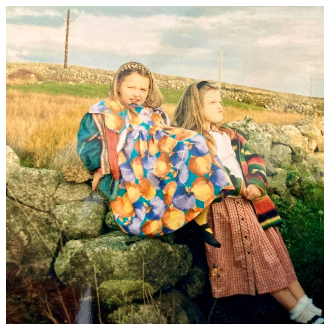 Two girls sitting on a stone fence (Courtesy of Edith Delaney)