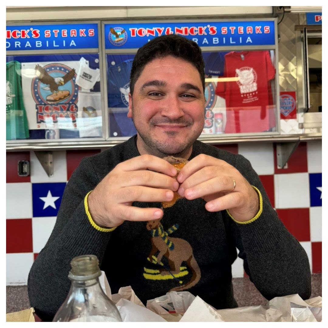 Smiling man eating a cheesesteak sandwich Courtesy of Daniel Taylor-Fowles)