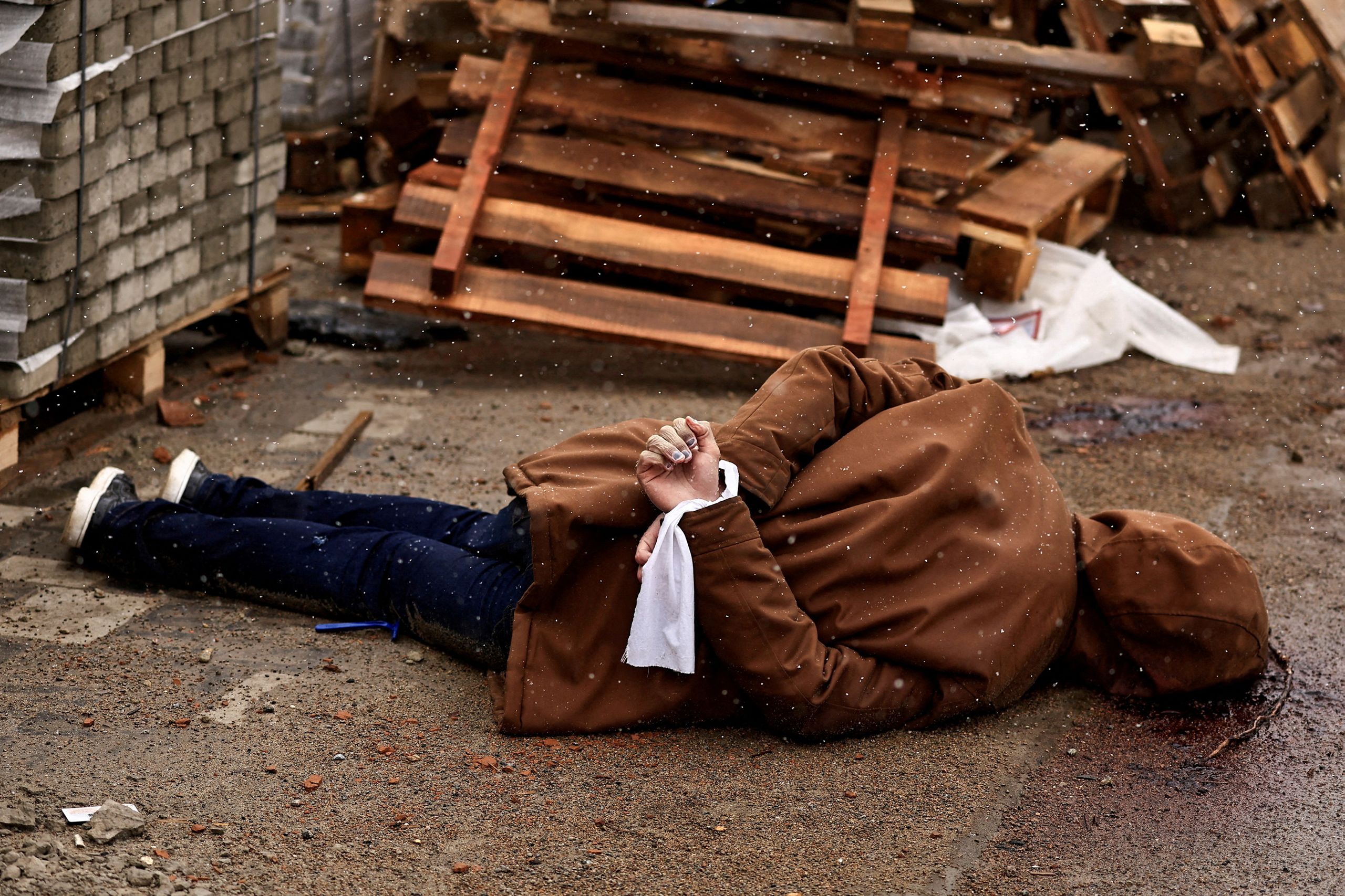 A body lies in the street with hands bound by white cloth. Residents said the person was shot by Russian soldiers during Russia's invasion of Bucha, Ukraine, on April 3, 2022. (© Zohra Bensemra/Reuters)