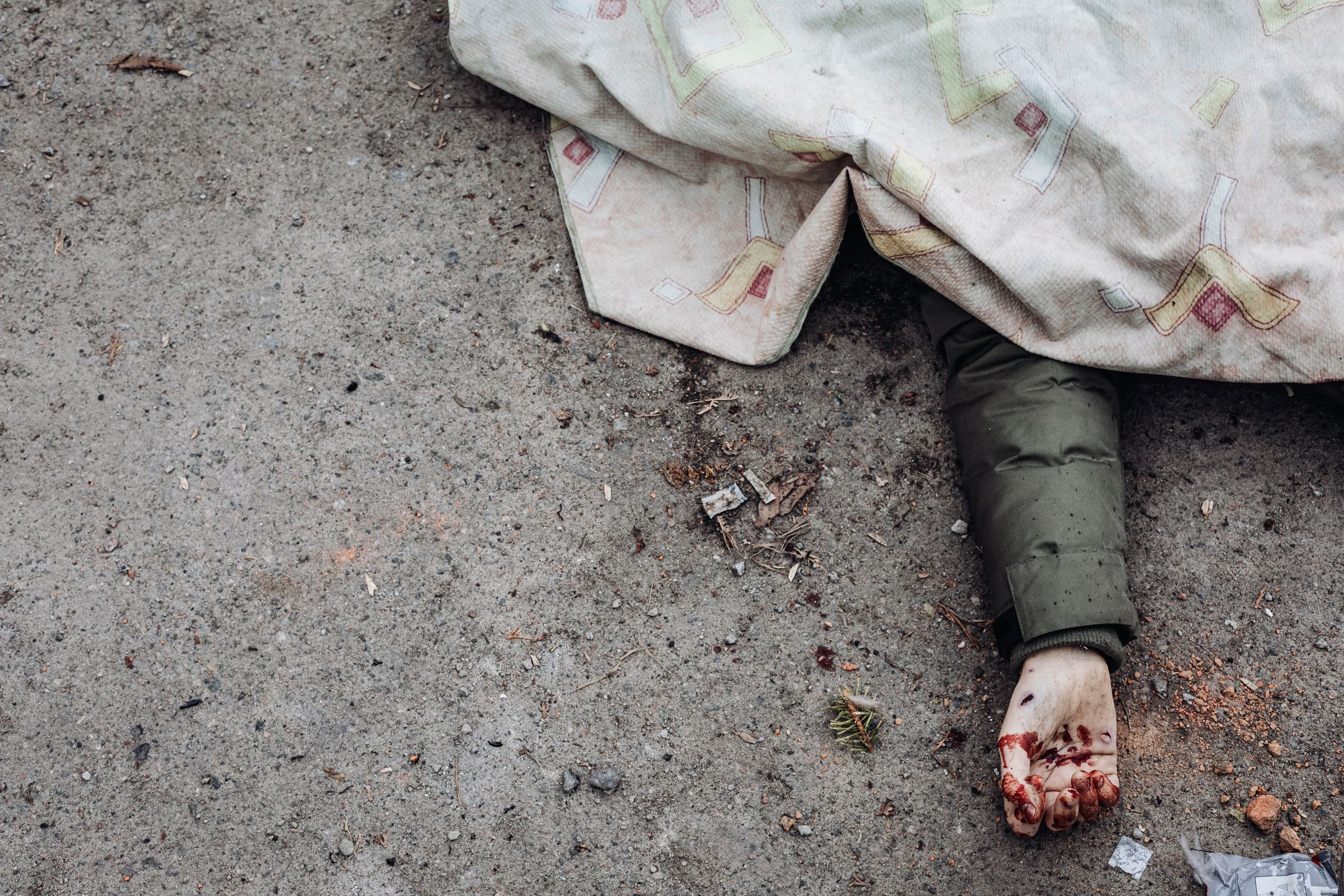 A person killed by Russian shelling lies covered in a street in Irpin, Ukraine, on March 6, 2022. (© Diego Herrera Carcedo/AP Images)