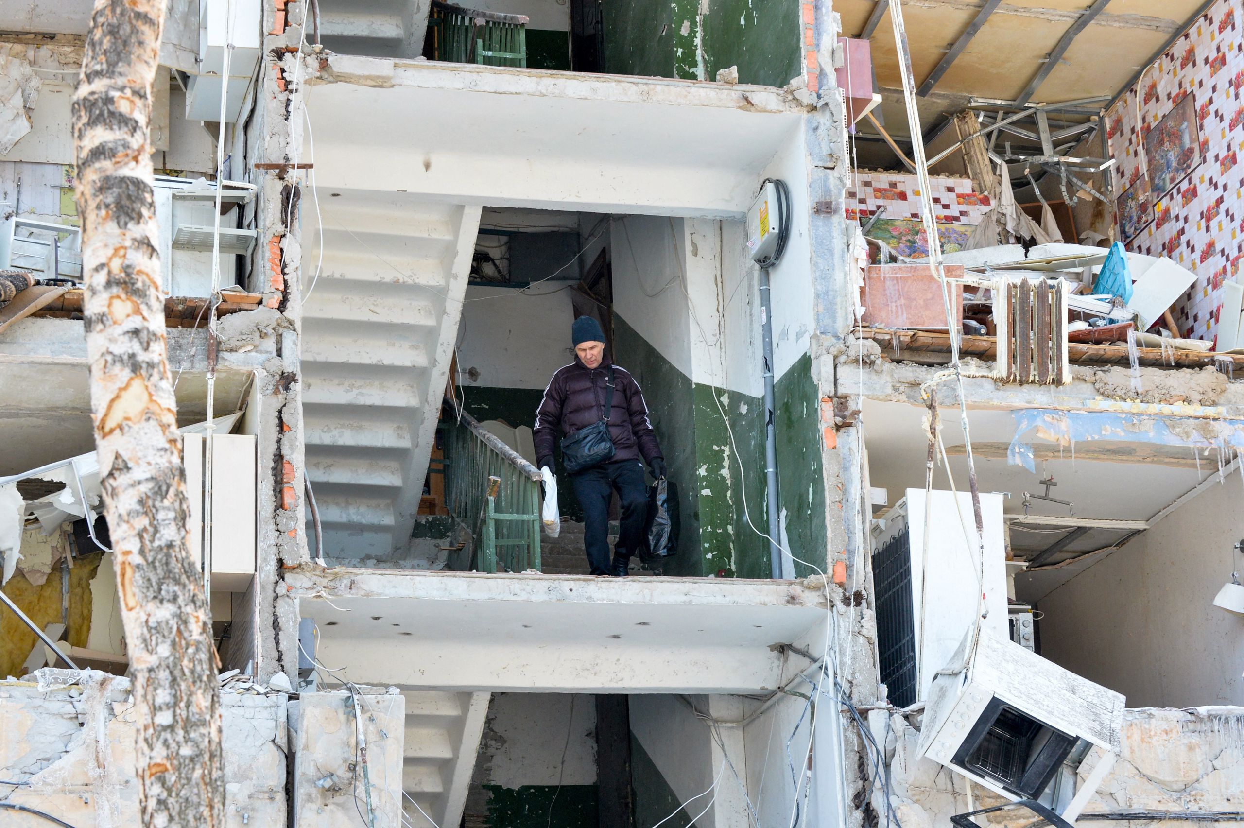 A resident carries belongings out of a heavily damaged apartment building after a Russian rocket exploded nearby in Ukraine's second-largest city, Kharkiv, on March 13, 2022. (© Sergey Bobok/AFP/Getty Images)