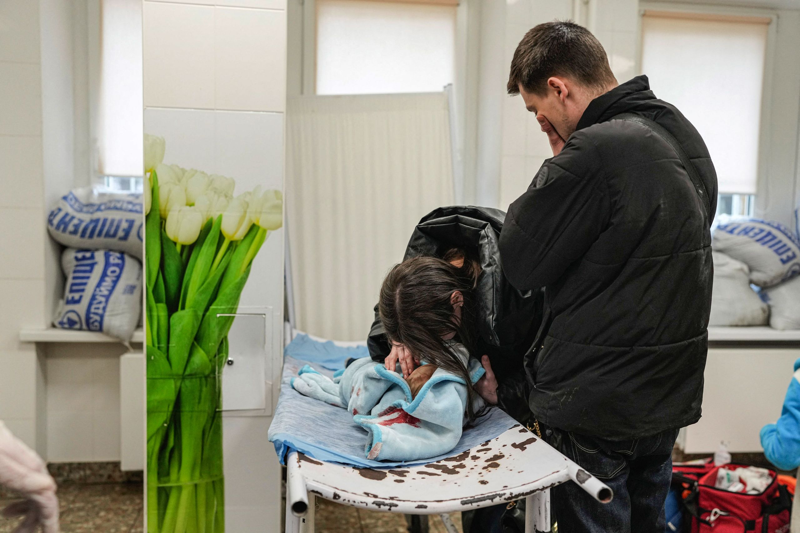 Marina and Fedor mourn over Kirill's body, killed in shelling, as he lies on a stretcher in the Mariupol hospital. (© Evgeniy Maloletka/AP Images)