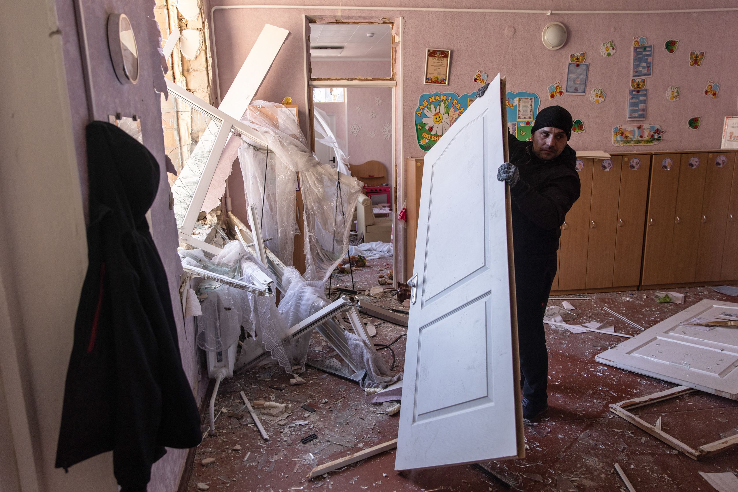 A man cleans up a classroom in a preschool that was damaged after a residential apartment complex was hit by a Russian attack on March 18, 2022, in Kyiv, Ukraine. (© Chris McGrath/Getty Images)