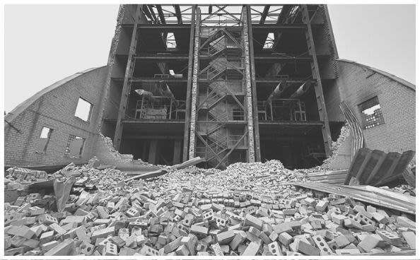 Un grand amoncellement de gravats devant un bâtiment détruit.