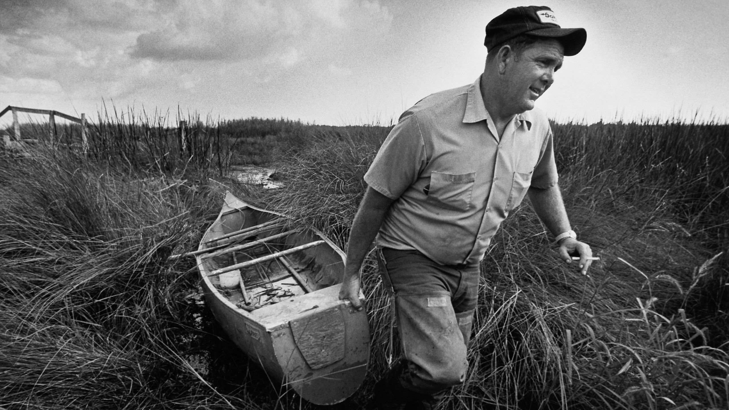 Man dragging a small boat through marsh grasses (© Ed Lallo/Getty Images)